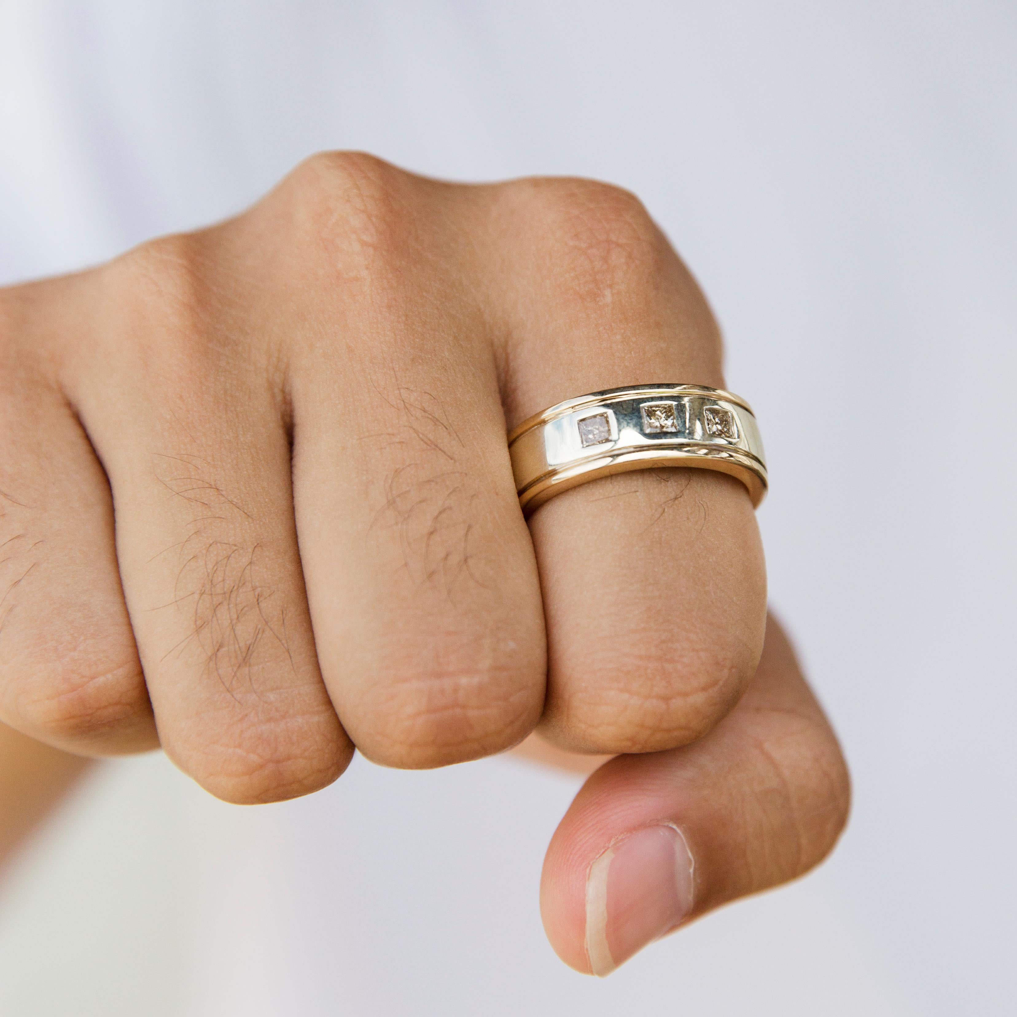Expertly forged in 9 carat yellow and white gold, this dapper men's ring is the hallmark of the sophisticated man. The elegant two-tone grooved band comes with an opulent high polish finish and three princess cut diamonds hammer set into the frontal