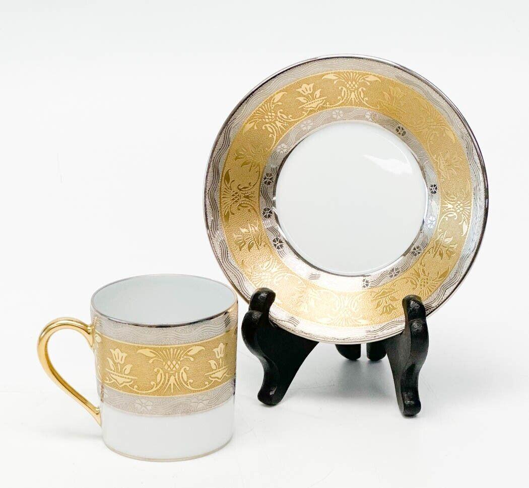 9 Christofle France porcelain demitasse cups and saucers in La Pavia. A white ground to center, gilt to the edge and with platinum bands to the rim with floral designs. Gilt to rims and handles. Each cup holds approximately 4 oz of liquid when