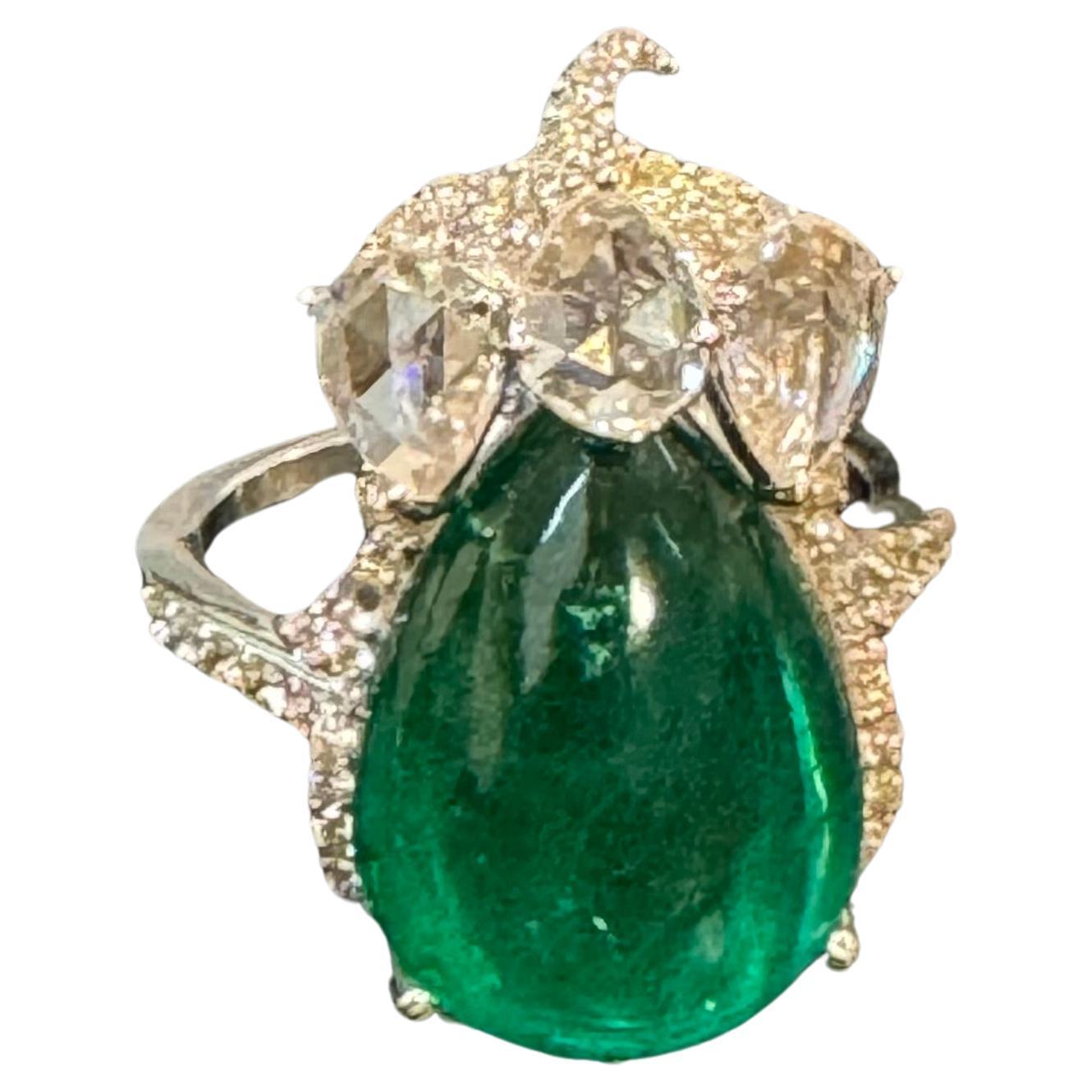 9 Ct Finest Zambian Sugar Loaf Pear Shape Emerald & 2 Ct Rose Cut Diamond Ring, Size 7, is a classic piece of jewelry showcasing a pear-shaped sugar loaf emerald from Zambia with exceptional color, quality, and luster. The emerald is complemented by