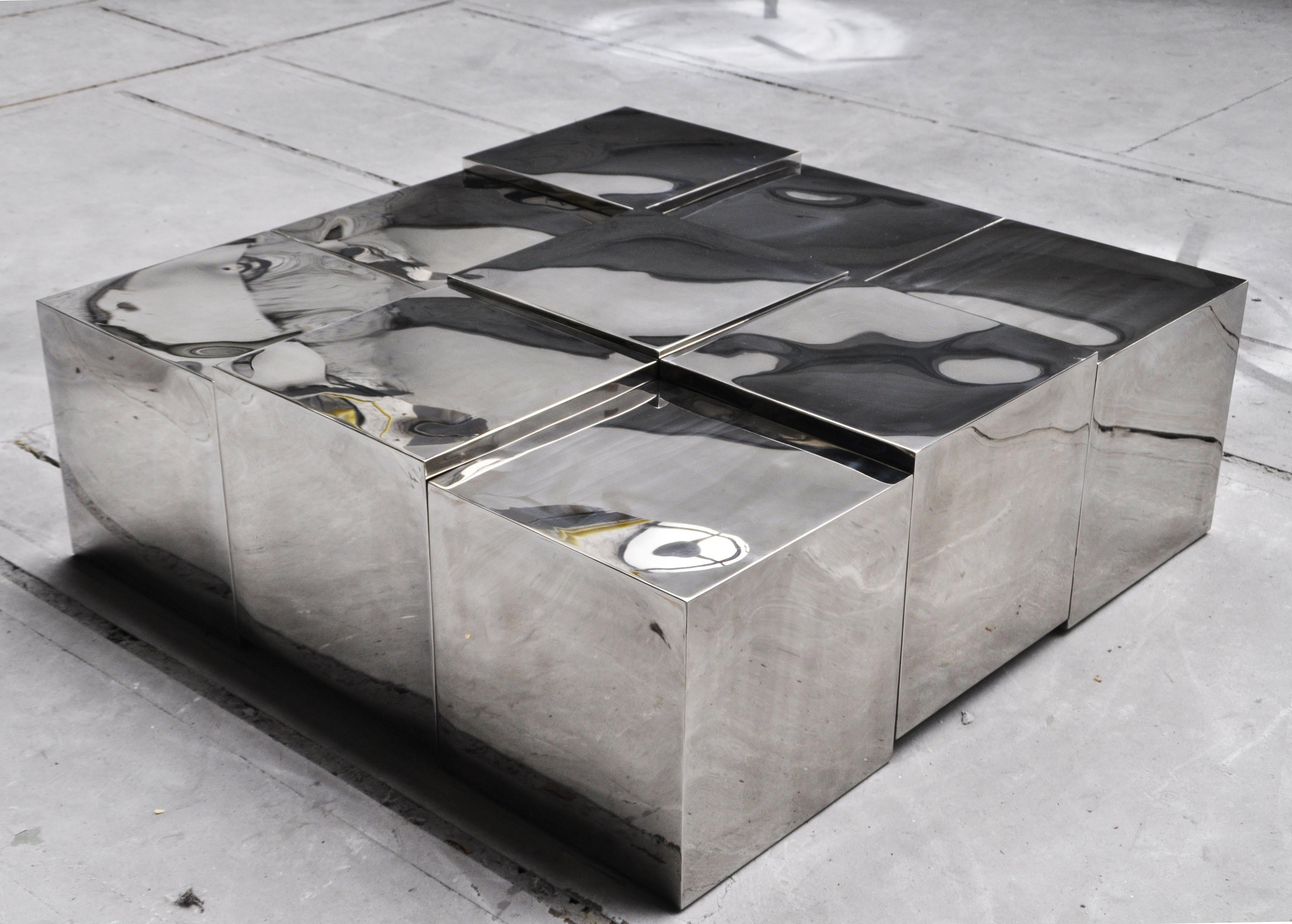 Table à 9 cubes par Pol Quadens 
Édition limitée à 8+4 pièces.
Dimensions : D 150 x L 150 x H 40 cm.
Matériaux : Acier inoxydable poli.

Pol Quadens est né à Bruxelles. Son père était actif dans les domaines des composites et de l'industrie