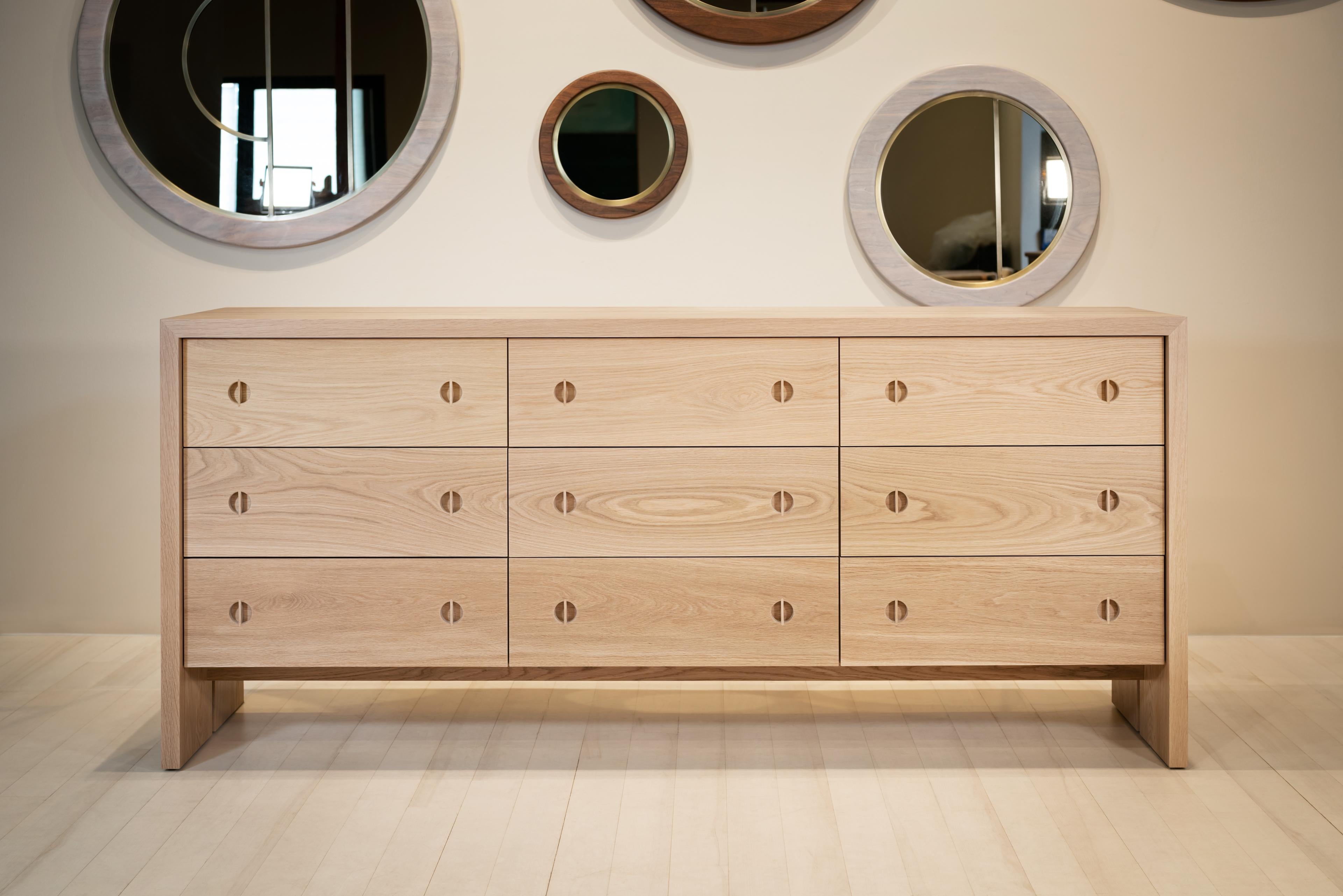 This modern wood dresser is hand-made in the United States with all hardwood construction. Characterized by its solid white oak body, minimalist walnut inlay detail, and unique split leg detail this contemporary wood dresser has deep storage drawers