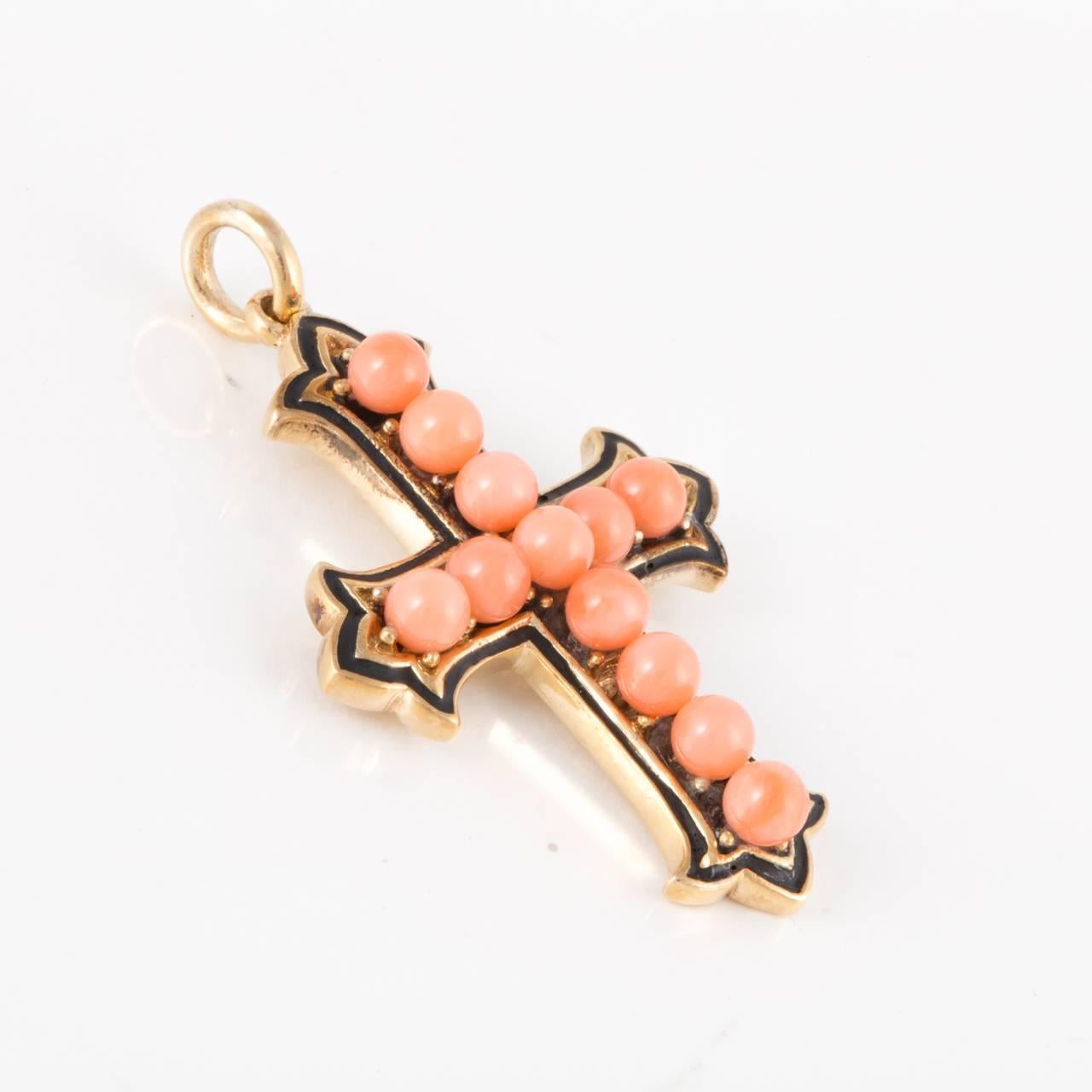 Victorian cross pendant composed of 9K yellow gold, featuring twelve coral beads down the center which are highlighted by blue enamel.  Measures 1 1/2 inches long and 1 1/8 inches wide. Circa 1870.