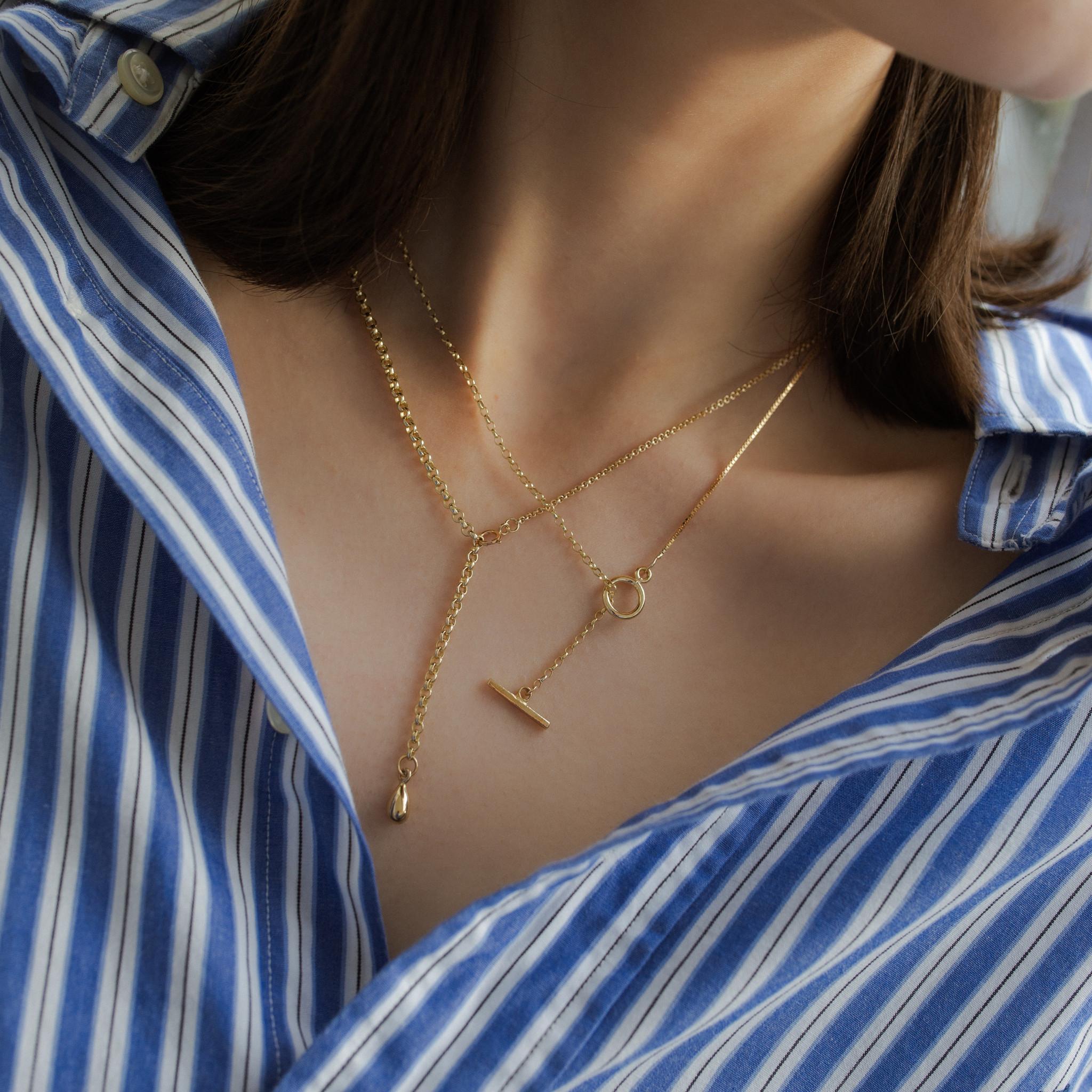 A modern take on the classic T-bar necklace, featuring both an oval belcher chain and a venetian box chain.

The lightness of the belcher chain and the weighty uninterrupted quality of the venetian box chain are more pronounced when paired