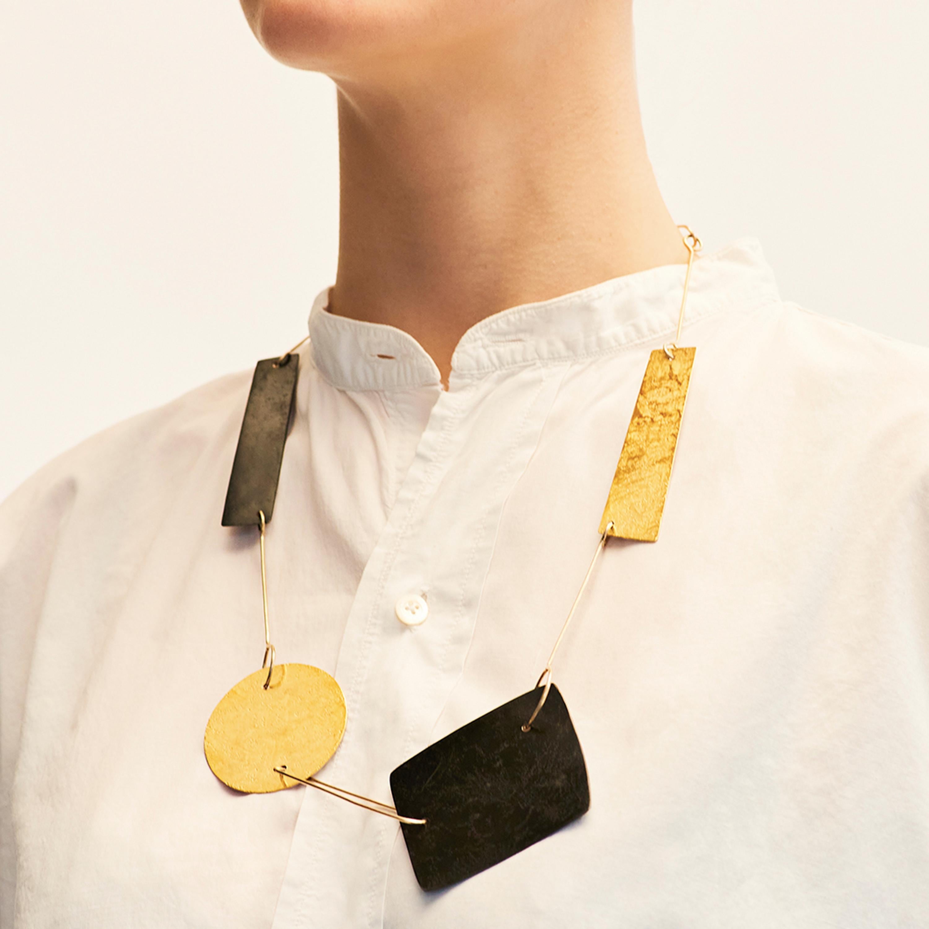 Catherine Le Gal brought together simple forms and combined materials to create her reversible Shapes Necklace. Catherine has hammered the surface of some elements, whilst others are smooth. Three simple black forms created from patinated steel,