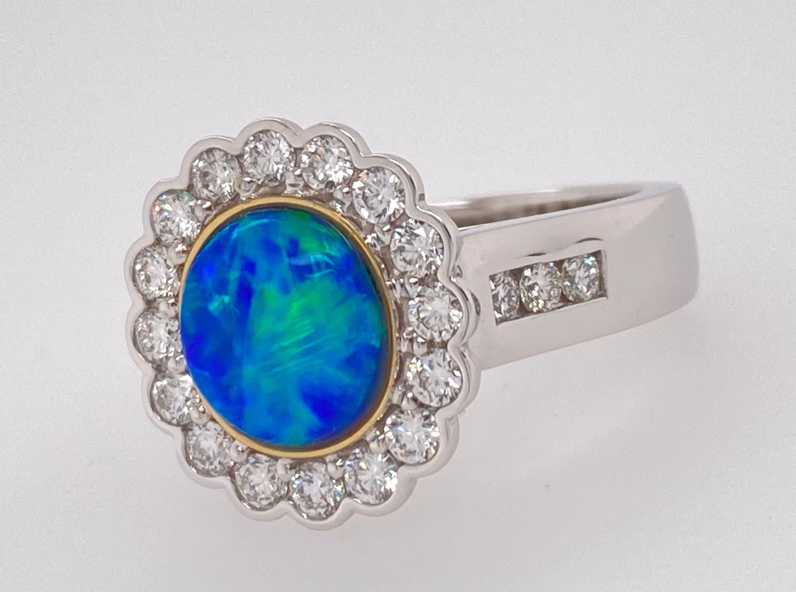 The center stone is a solid lightning ridge crystal opal set in a bezel setting. There is sixteen round brilliant cut diamonds surrounding the center stone forming a cluster head. Each shoulder contains three round brilliant cut diamonds in channel