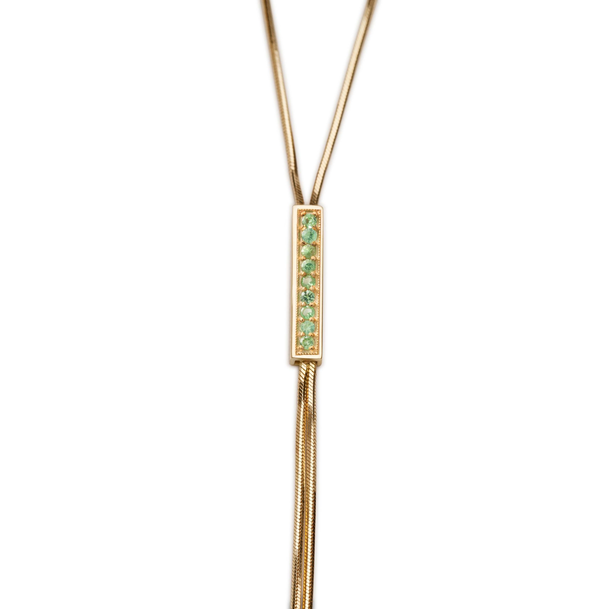 This captivating necklace from Iosselliani drapes along the neck with a 9 Karat gold custom made chain for a minimal, elegant design. The lariat is bejeweled by a central bar with 0,21 green sapphire pavé to maximise visual impact. Round neck lenght