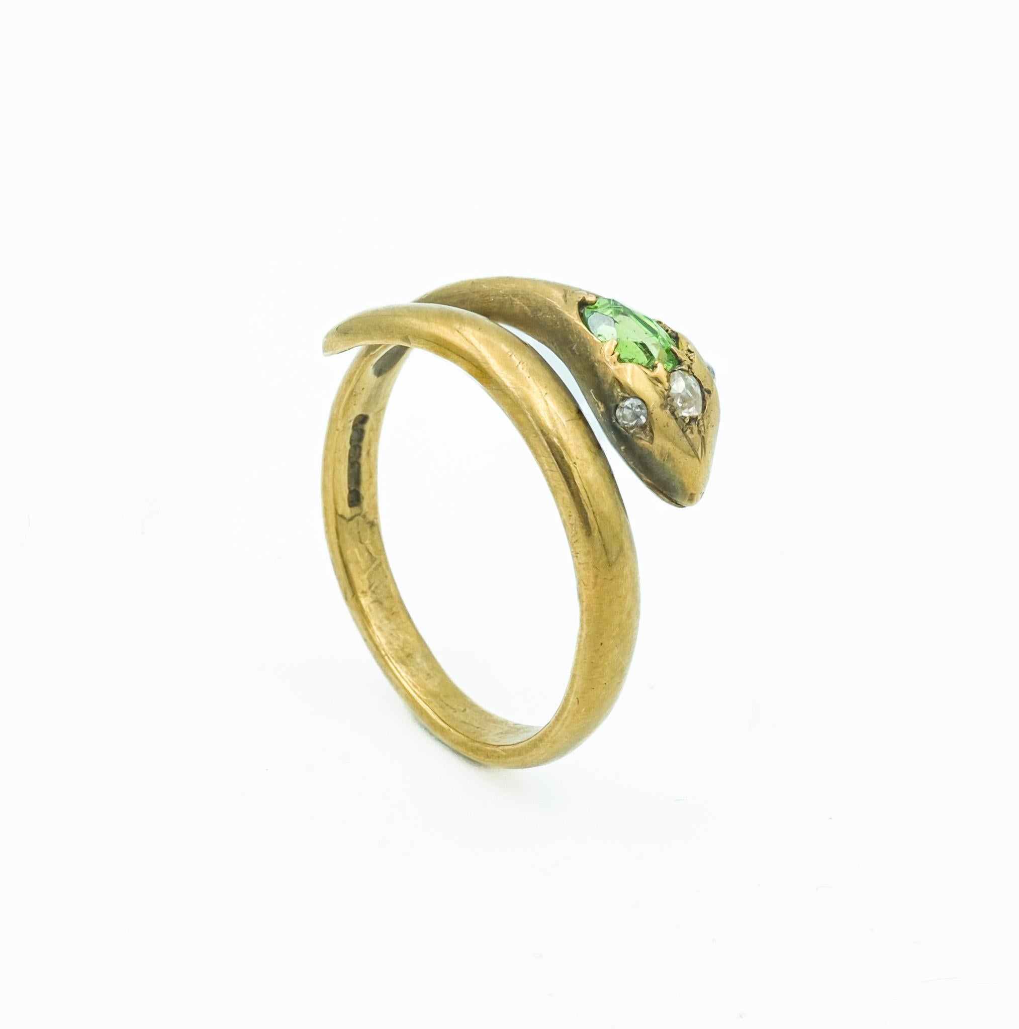 Discover the mystique of this enchanting 9 karat gold snake ring, a masterpiece of British craftsmanship. This piece features a stunning demantoid garnet as the snake's head, its vibrant green hue capturing the essence of nature's beauty.