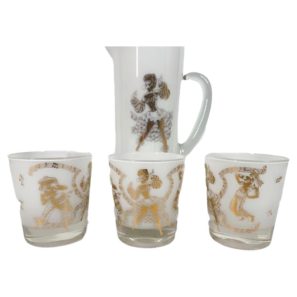 Nine-piece cocktail pitcher set, clear glass with white frosted interiors having Calypso performers in 22 karat gold on the exterior. Set consists of a large pitcher with applied handle and ice dam lip along with 8 old fashioned glasses.