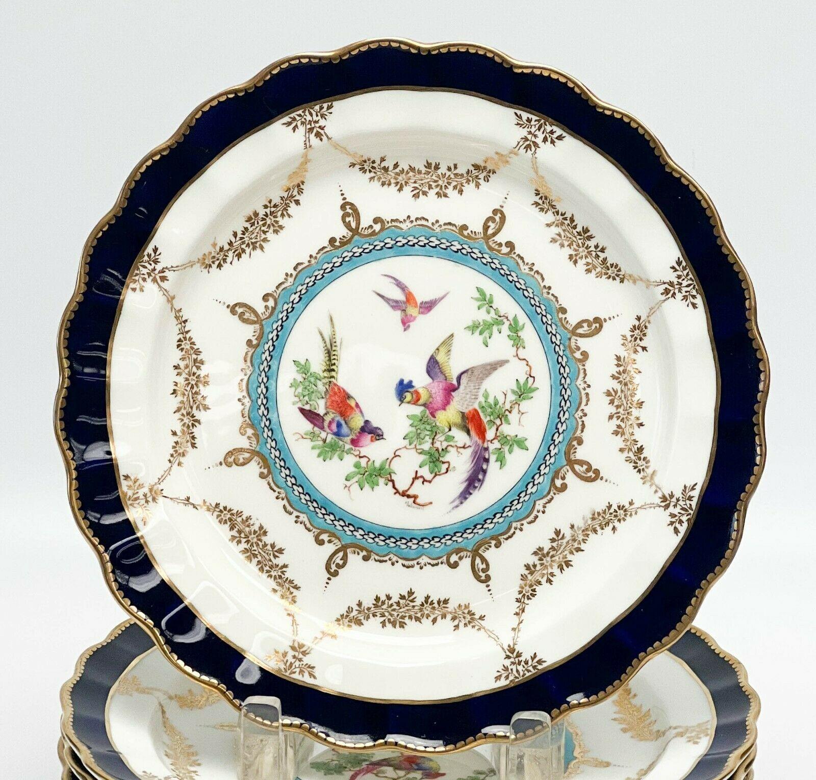 9 Royal Worcester for Tiffany & Co. porcelain dessert plates artist signed, 1925

A white ground with a band of cobalt blue to the scalloped edge. Gilt garland decoration, hand painted birds to the center, artist signed 