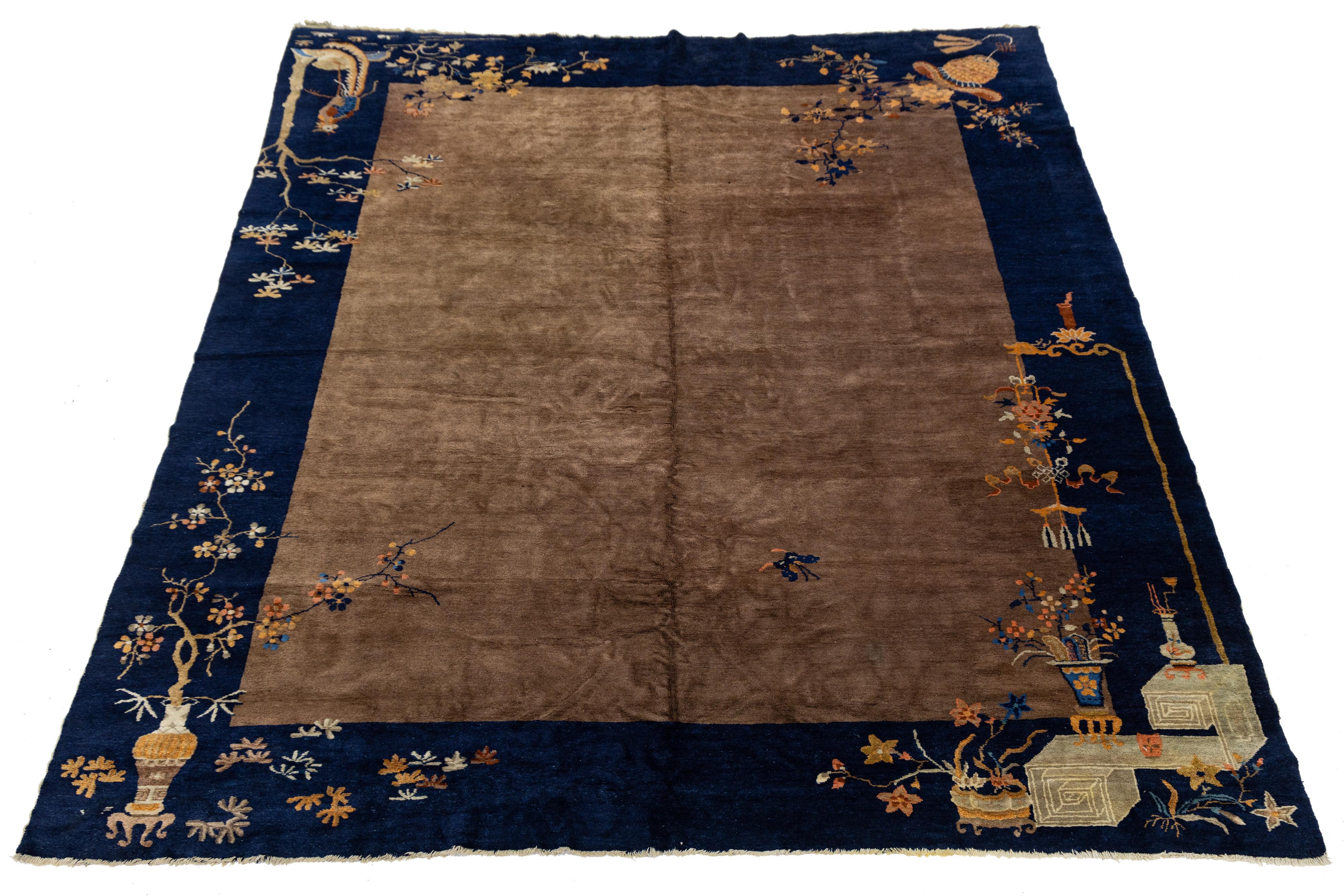 Ancien tapis chinois Art Déco, noué à la main en laine avec des motifs d'angle symboliques et de riches abrasions. Il s'agit d'un champ brun minimaliste encadré d'un indigo profond, orné de lotus, de vases et d'oiseaux. Une pièce rare du 20e siècle
