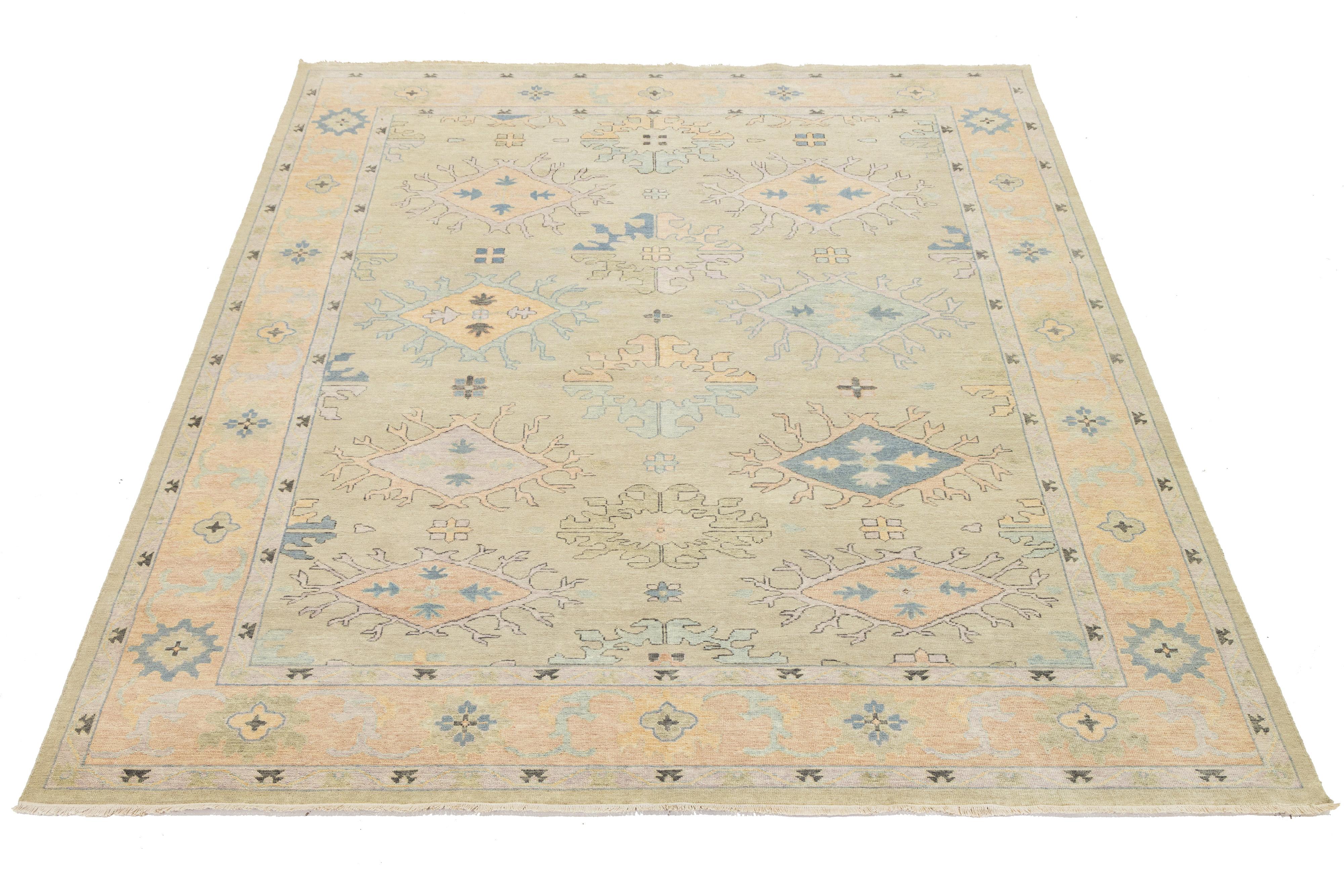 Questo tappeto contemporaneo in lana in stile Oushak, grande quanto una stanza, fonde perfettamente il design moderno con l'artigianato tradizionale. Caratterizzato da un sorprendente sfondo beige, è elegantemente decorato con motivi in una sottile
