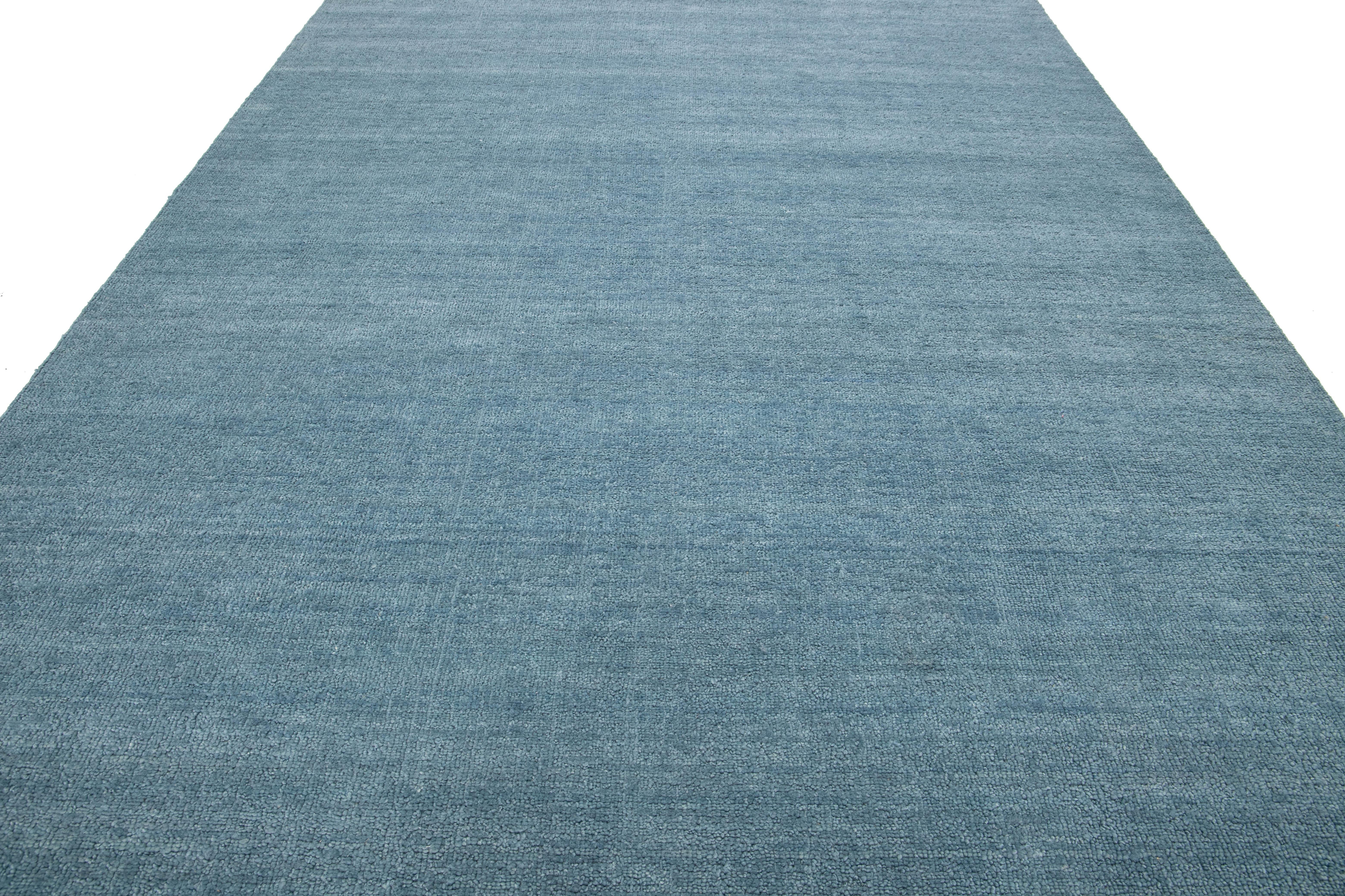 Esta moderna alfombra india de lana anudada a mano ha sido elaborada por expertos artesanos y presenta un diseño limpio. Su suave color azul actúa como telón de fondo versátil, lo que le permite armonizar sin esfuerzo con toda una gama de estilos de