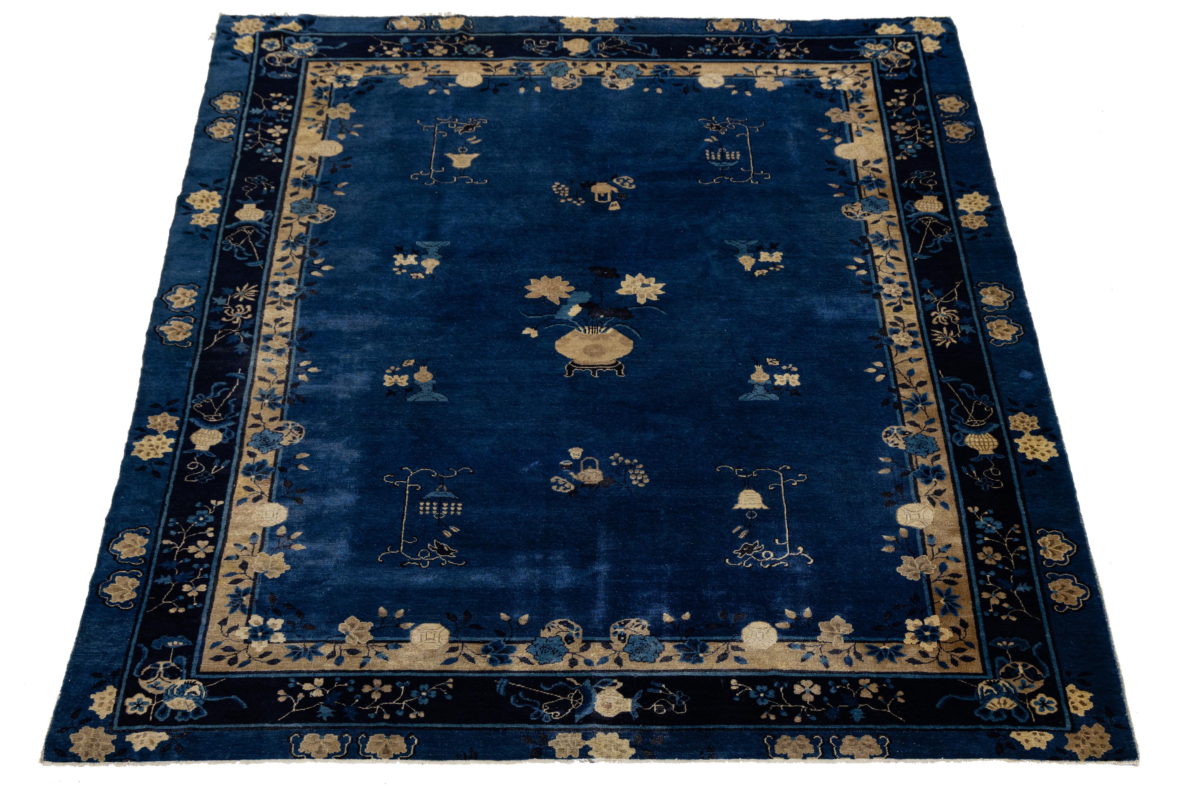 This antique Chinese Art Deco rug is hand-knotted from high-quality wool and features a deep navy blue background with a tan floral design, elegantly framed by a matching tan border.

This rug measures 9'1