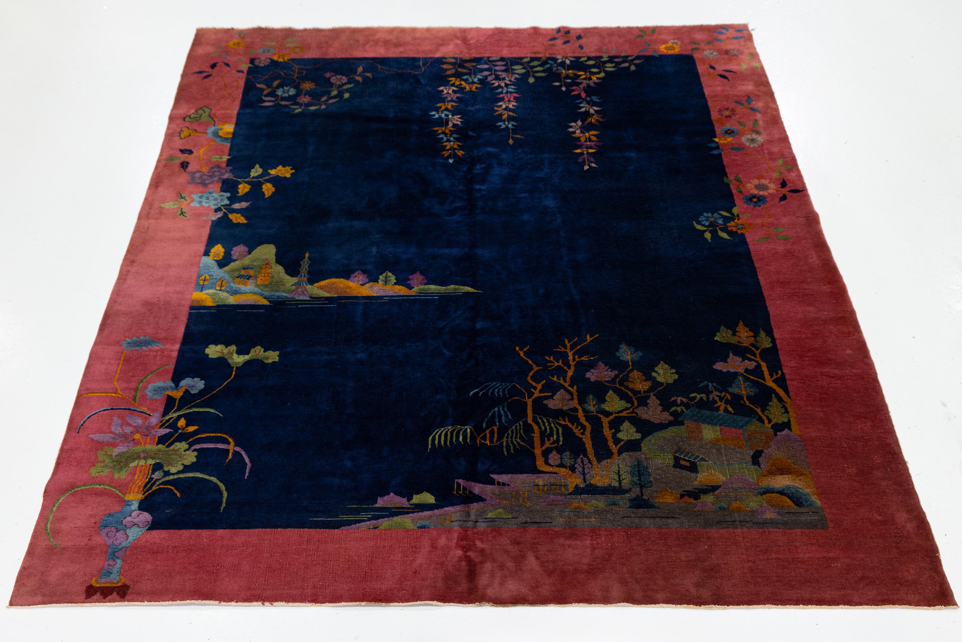 Tapis chinois ancien de style Arte Antiques, noué à la main en laine avec des paysages de village et des motifs floraux. Il s'agit d'un champ bleu marine profond encadré d'une bordure rose, représentant des maisons, des arbres, des papillons et la