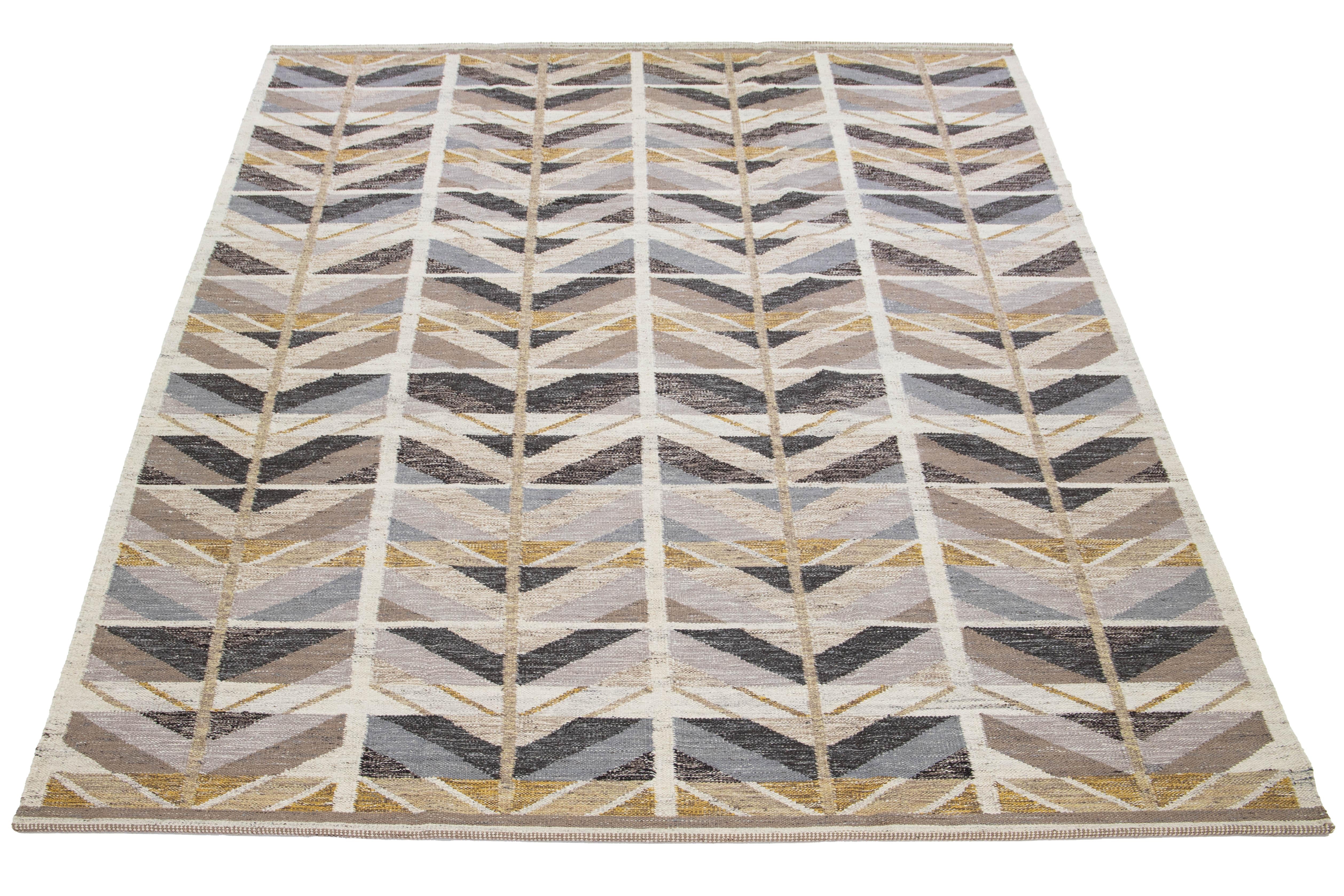 Scopri la bellezza di questo raffinato tappeto in stile svedese, sapientemente annodato a mano con lana di alta qualità. La sua raffinata palette di colori è caratterizzata da una miscela omogenea di grigio, beige e marrone, arricchita da vivaci