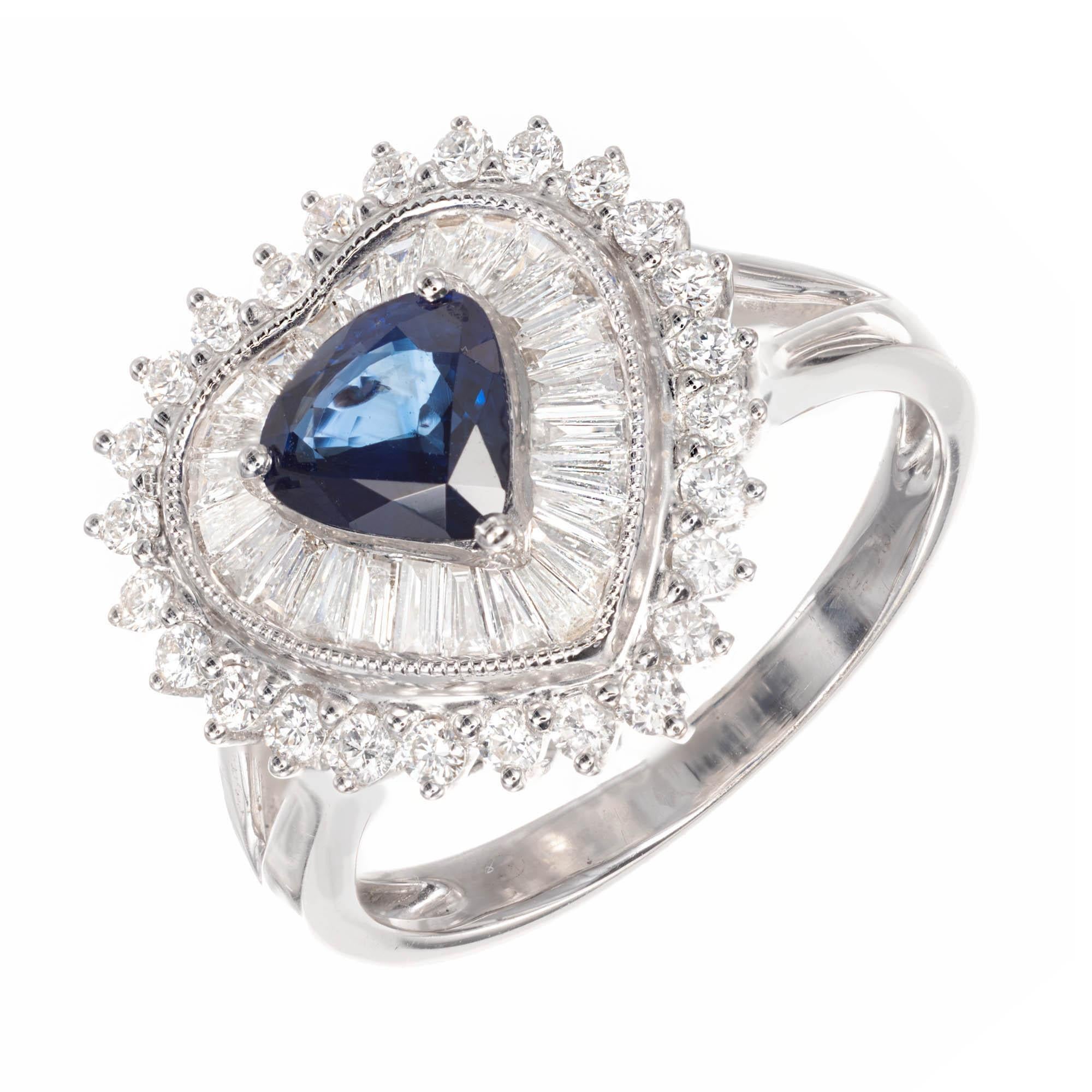 Sapphire and diamond cluster cocktail ring. Pear shape Sapphire is set center stage with a heart shape bezel surrounding Sapphire with tapered baguette Diamonds. Finishing with an outer heart shape of prong set round brilliant cut Diamonds.

1 pear