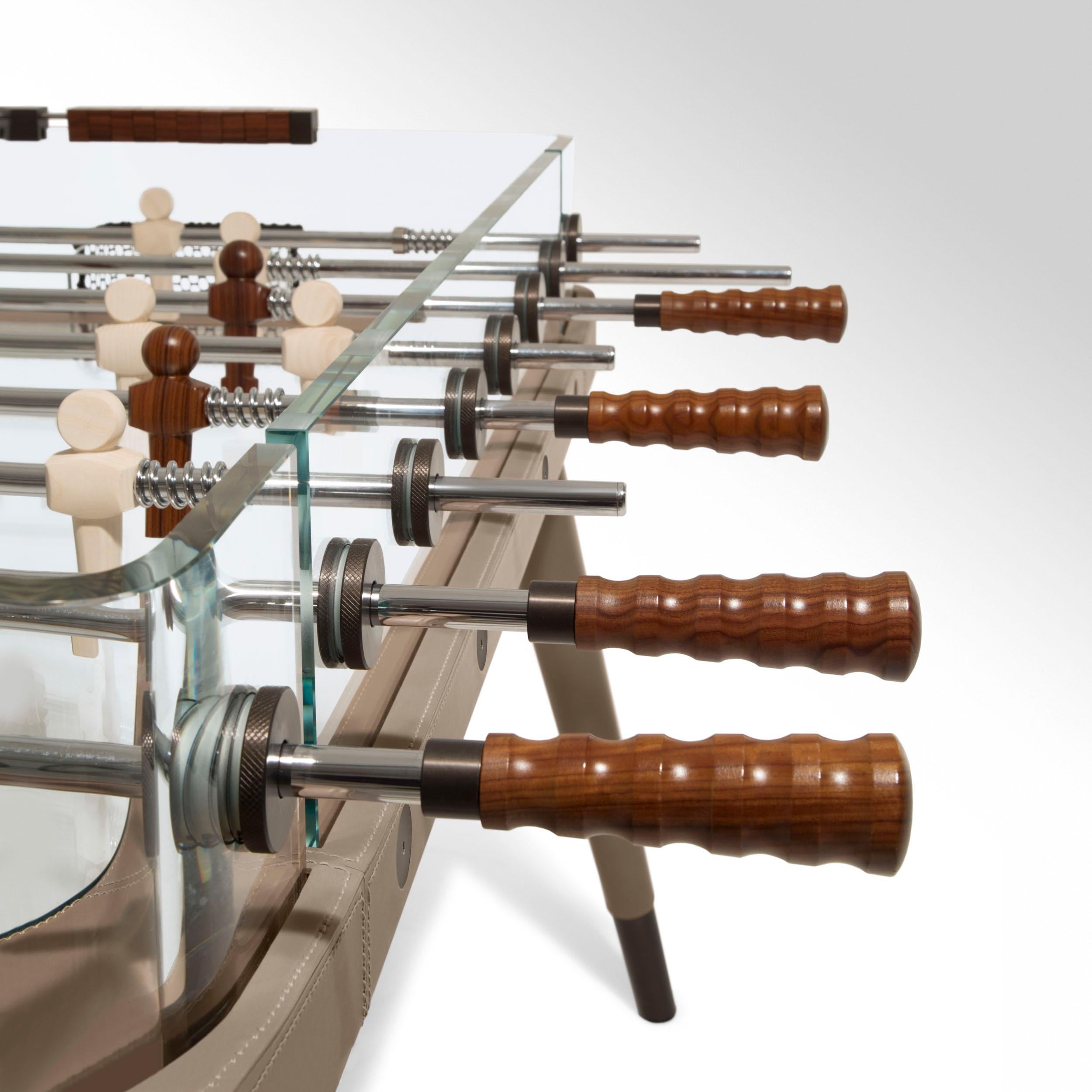 Table football with tub and curved sides made of extra-clear glass, thickness 8 - 15 mm.
The legs and frame are made of wood, covered in leather, available in different shades, making this table soccer
one of its kind. The knobs are pau ferro and