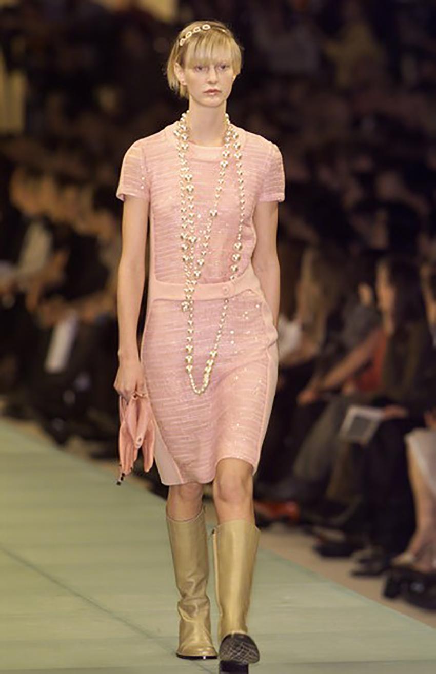 CHANEL

The Chanel dress is made of pink wool fabric and decorated with matching sequins. 
Decorated with a belt with buttons and the brand logo. 
Short sleeves, fitted silhouette. 
Silk lining to match. 
Zip fastening at the back. 


Pre-owned,