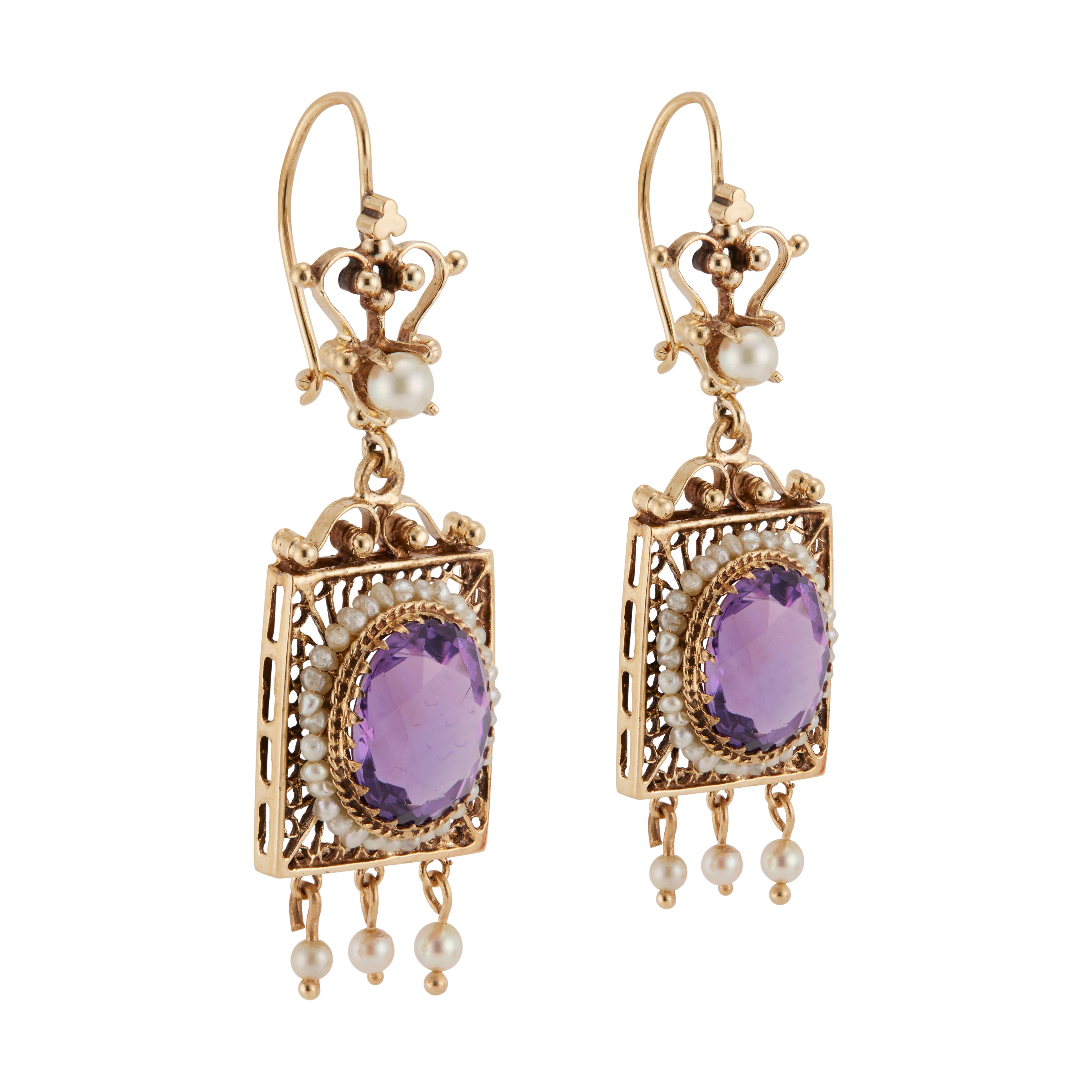 1940's Victorian revival Amethyst and pearl dangle earrings. 2 oval shaped genuine amethysts, each with a halo of pearls set in 14k yellow gold dangle settings accented with 3 pearl dangles on each frame with a pearl above the frame.  

2 oval