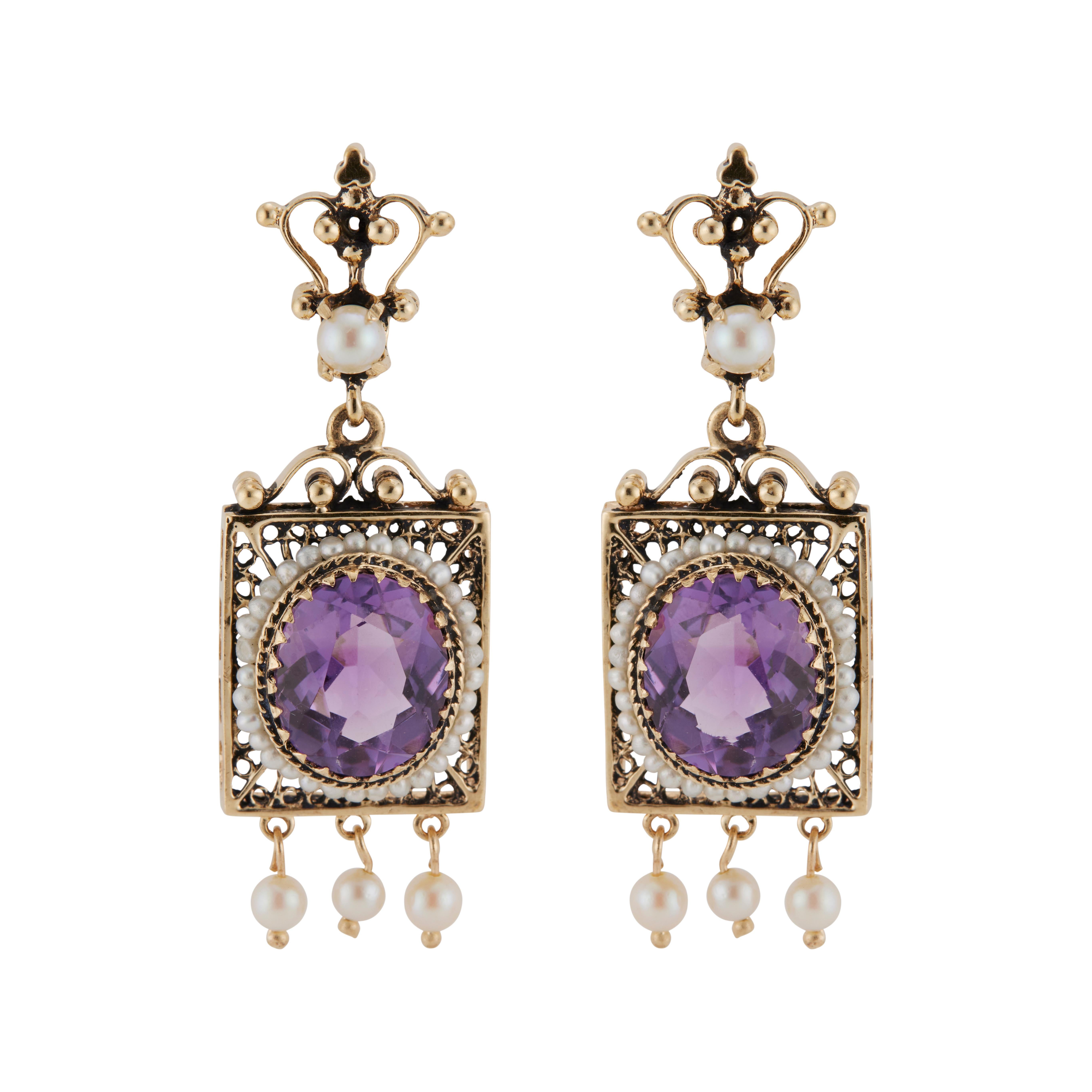1940's Victorian revival Amethyst and pearl dangle earrings. 2 oval shaped genuine amethysts, each with a halo of pearls set in 14k yellow gold dangle settings accented with 3 pearl dangles on each frame with a pearl above the frame.  
    
12