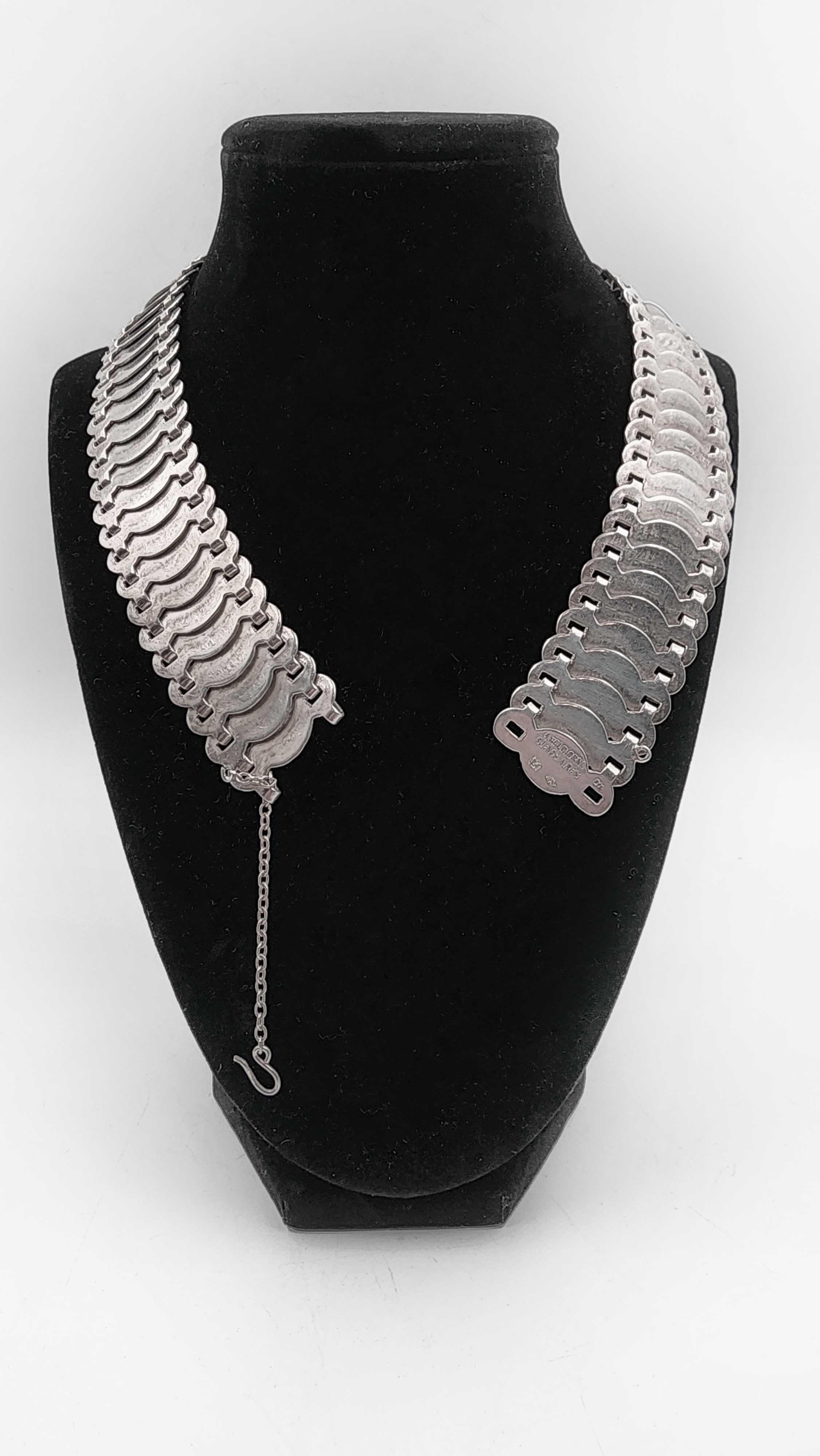 900 Silver Choker Necklace by Antonio Belgiorno
This 900 silver choker necklace by Antonio Belgiorno is a modern and elegant piece that will add a sophisticated touch to any outfit. The design features wide, flat links arranged in a sequence that