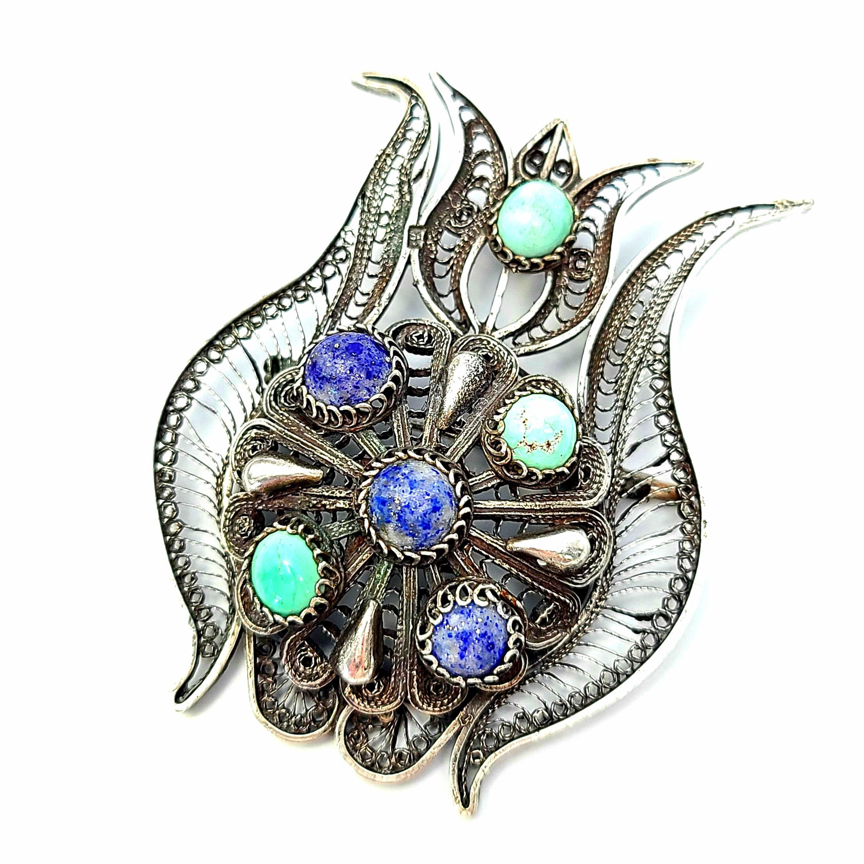 900 silver and blue stone Lotus flower pin/pendant.

This beautiful Egyptian silver lotus flower features blue stones that appear to be turquoise and lapis lazuli, and an intricate filigree design. It can be worn as a pin or a pendant.

Measures