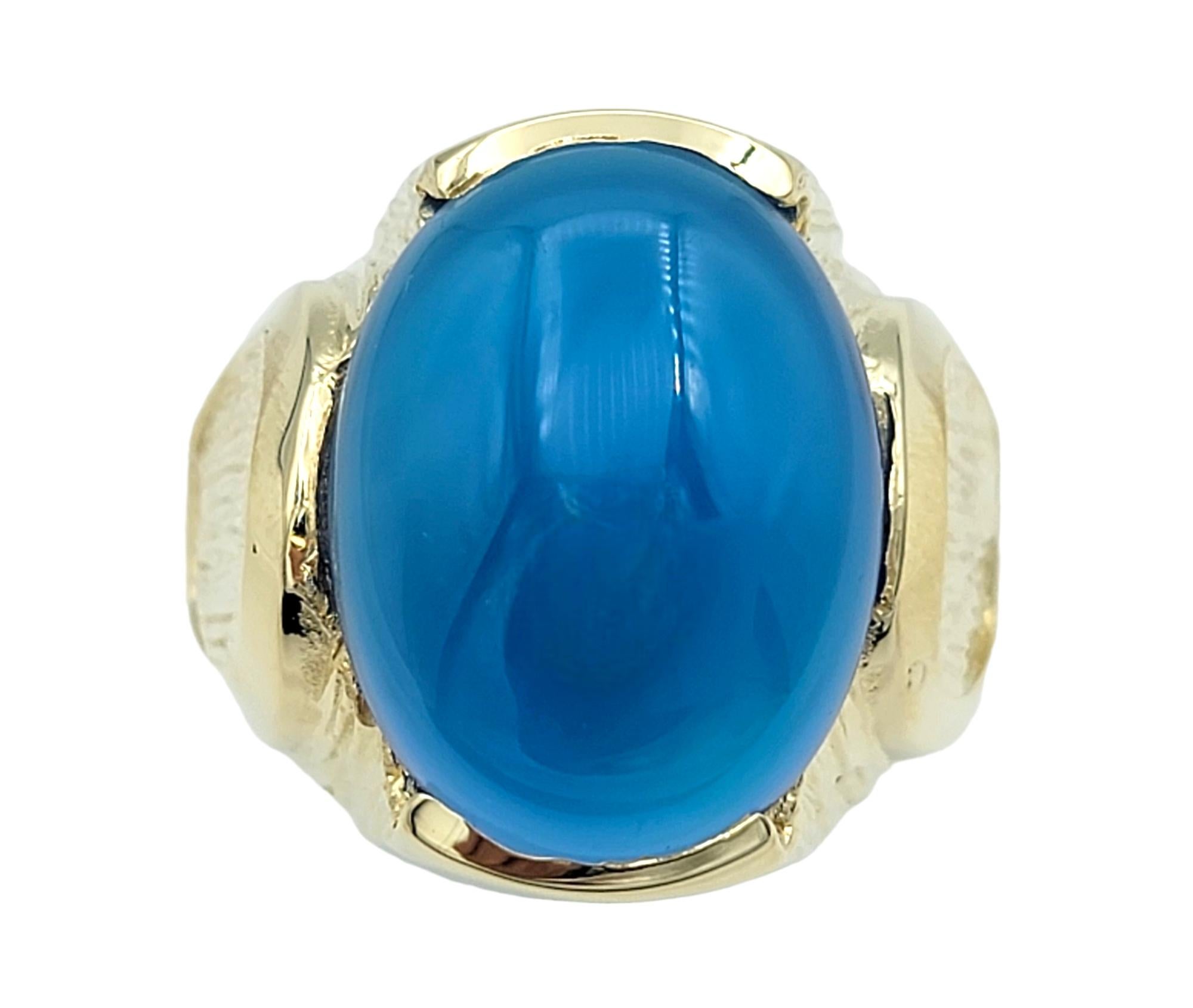 Ring Size: 9

Featured here is an enchanting 9.01 carat blue chalcedony ring which is masterfully crafted in 14 karat yellow gold. This exquisite ring features a captivating dyed blue chalcedony, its smooth, polished surface reflecting its ethereal