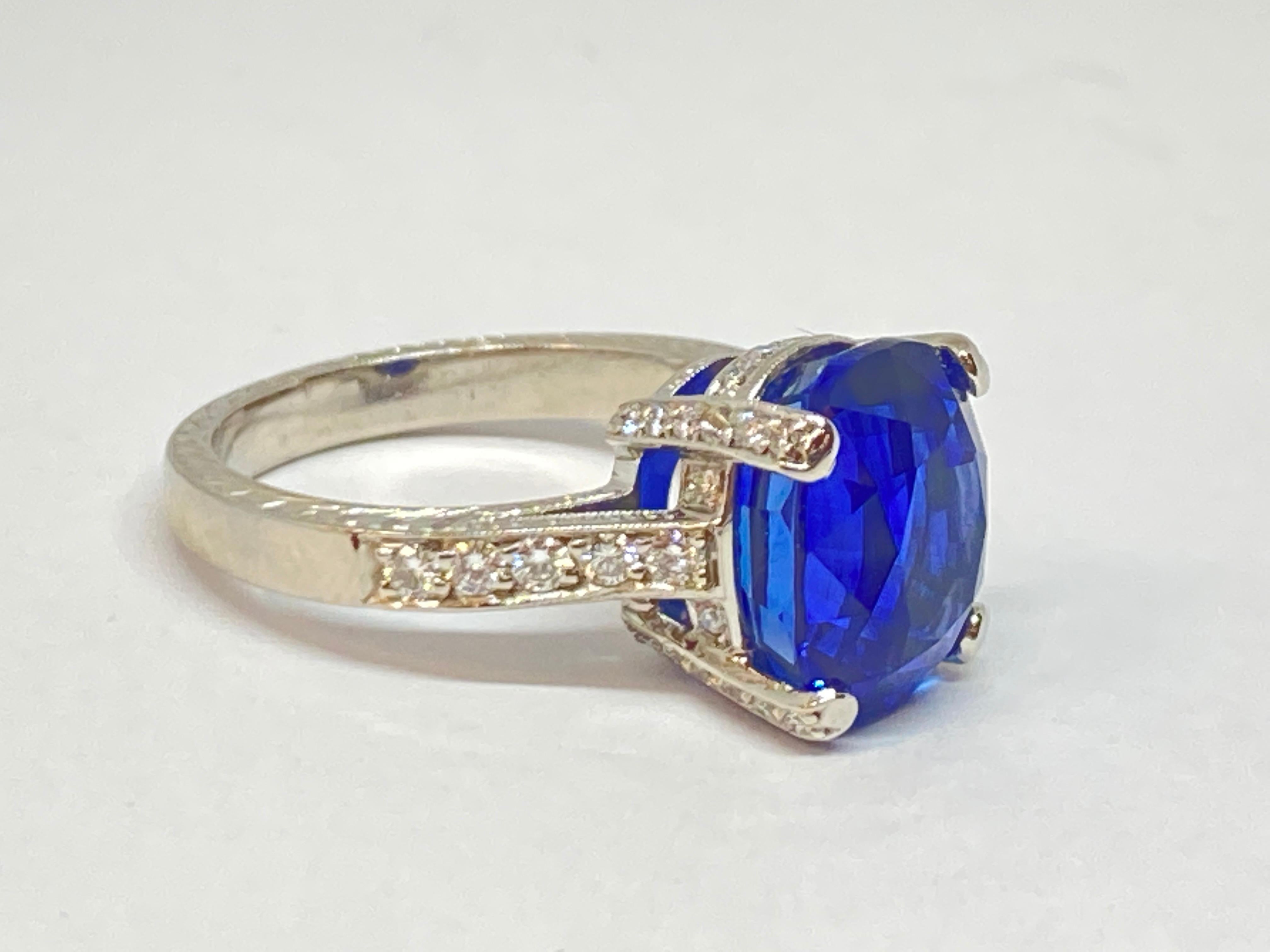 A striking blue sapphire weighing 9.02 carats, flanked by a diamond pave set mounting, pave set gallery and profile. The stone is held in by four strong prongs and the ring has a polished shank. 

9.02-carat cushion mixed-cut blue