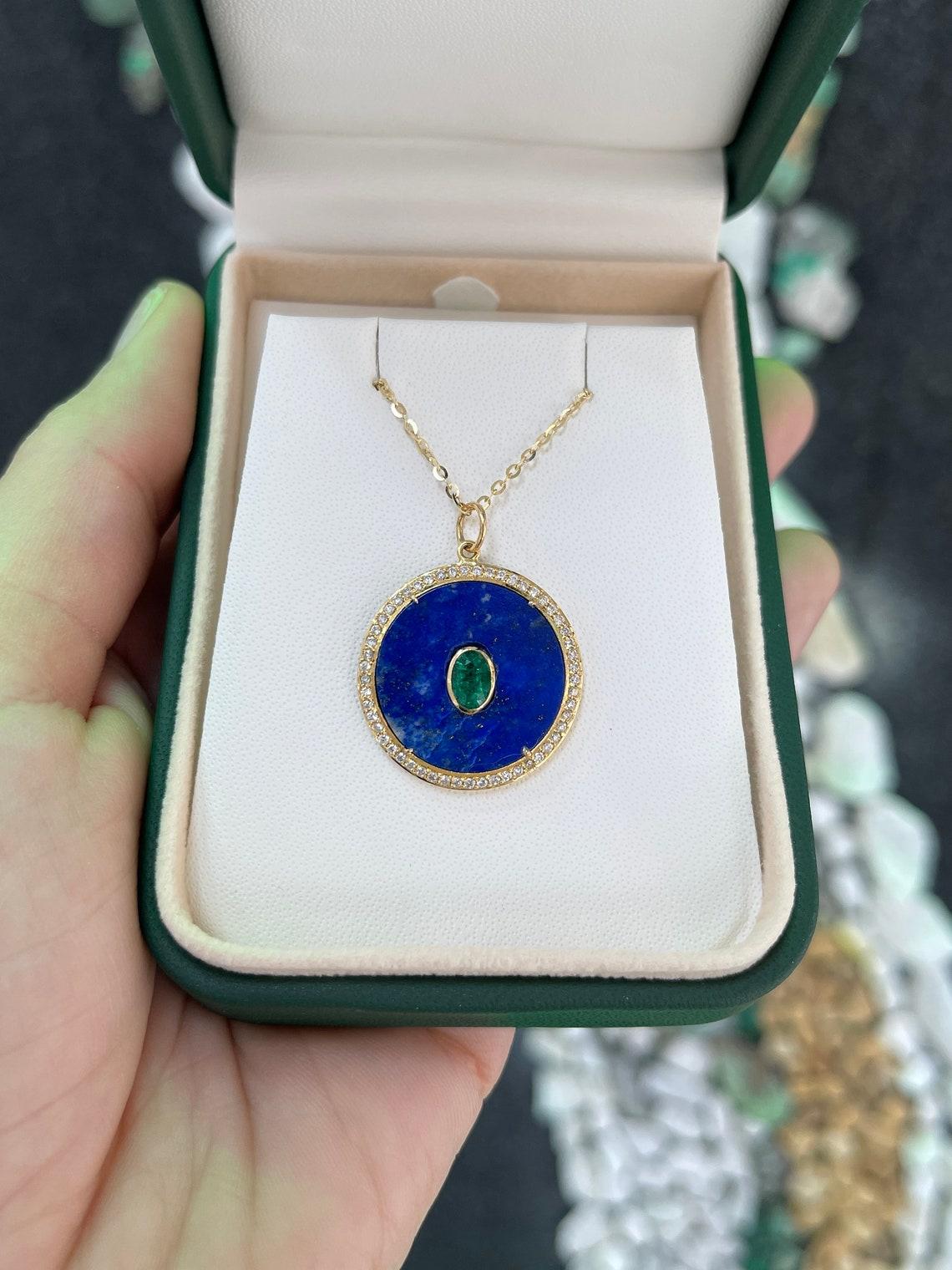 Unser exquisiter Smaragd-, Diamant- und Lapislazuli-Anhänger ist ein fesselndes Meisterwerk, das leuchtende Edelsteine und zeitlose Eleganz nahtlos miteinander verbindet. Im Mittelpunkt steht ein natürlicher Smaragd im Ovalschliff, der vertikal in