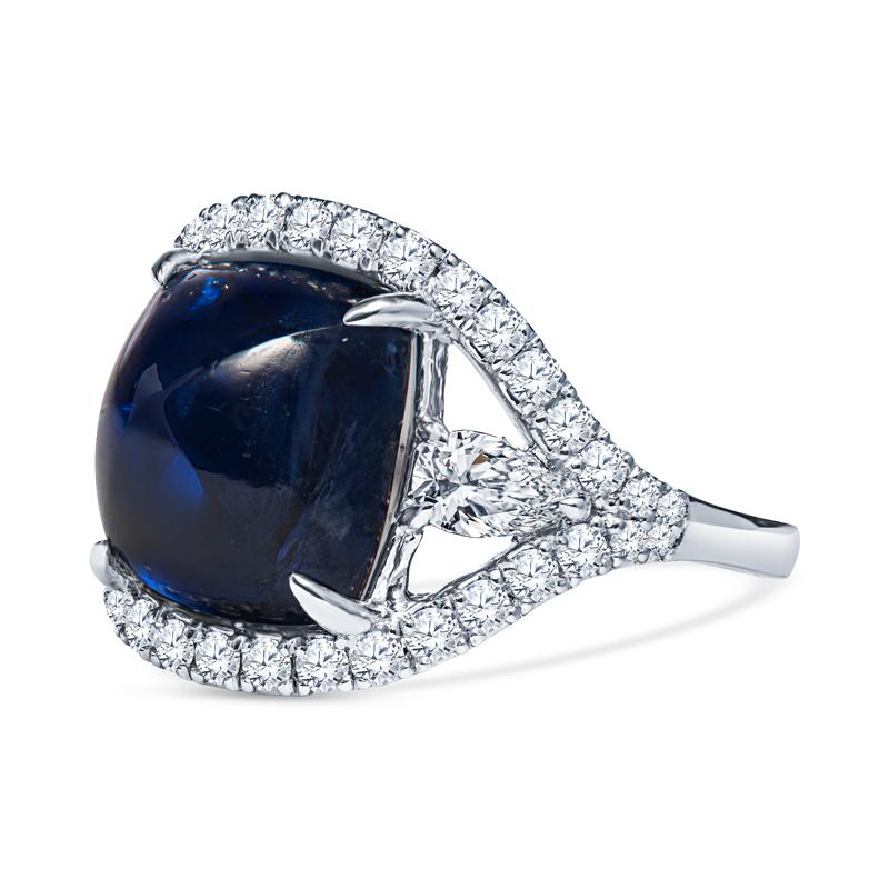 This very unique ring features a 9.06 carat cabochon sugar loaf natural blue sapphire accented by 2 pear shaped diamonds and 0.54 carat total weight in round diamonds set in 18 karat white gold. This ring is a size 6 but can be resized upon request.