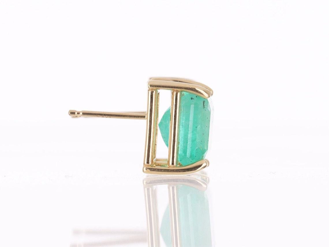 Hier ist ein wunderschöner Satz kolumbianischer Smaragdstecker im Asscher-Schliff aus feinem 14-karätigem Gelbgold zu sehen. Es handelt sich um mittel-hellgrüne Smaragde mit sehr guter Transparenz, die von einer floralen 14K-Goldfassung mit vier