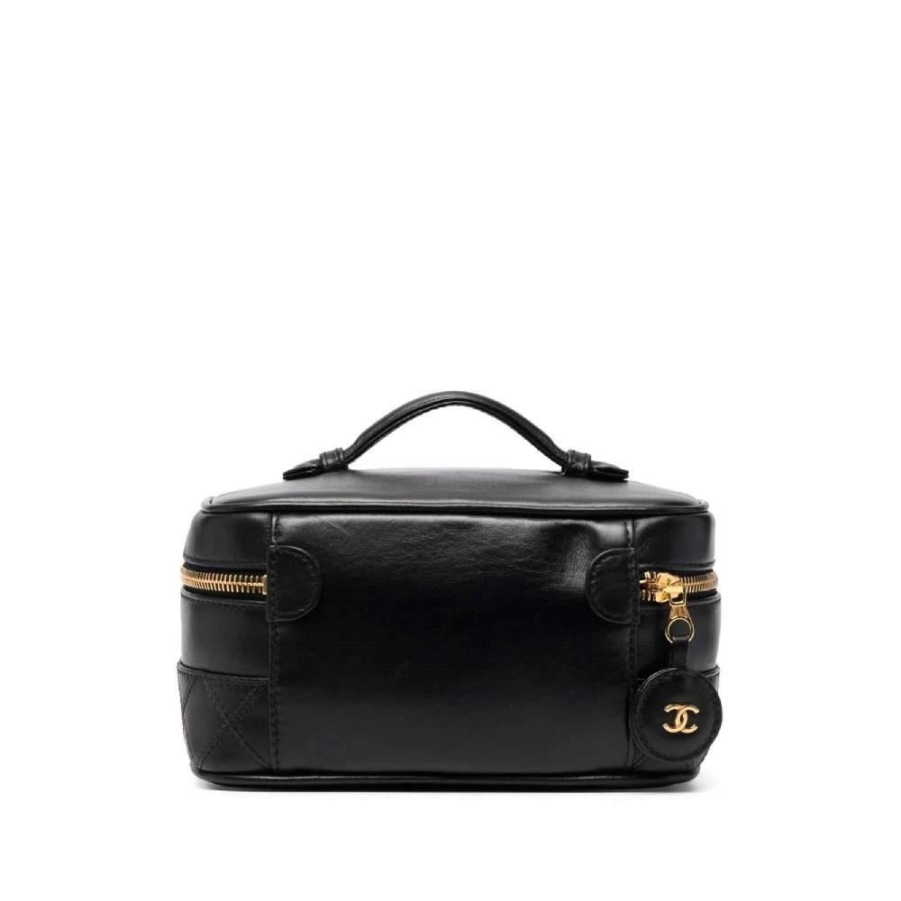 Chanel black leather vanity case with quilted lower band. Flat handle, gold-tone metal zip fastening, puller leather charm woth double C appliqué. Single inner compartment with a small elasticated pocket. Authenticity card.

Measurements
Heigh: 10
