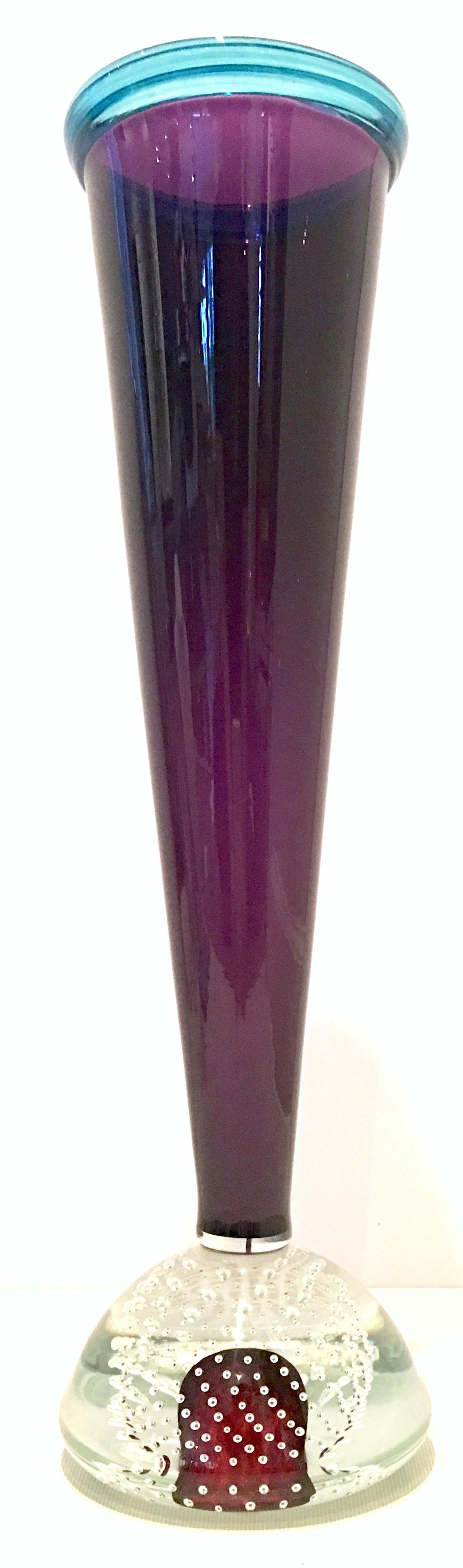 1990s hand blown Murano style art glass vase by, Young & Constantin. This Murano Style, American Blown Glass Vase of amethyst and blue features a cylindrical shape with a oval bulbous inclusive bubble foot. Signed on the underside, Young &