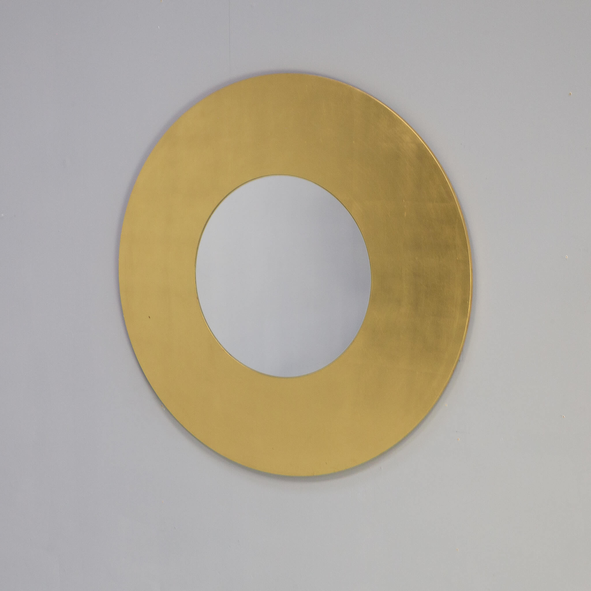 Designed by Lella and Massimo Vignelli, Lago Dorato is a refined and precious round mirror produced by Morphos, which is characterized by an elegant circular wooden frame with gold leaf gilding. Refined lines, perfect for decorating any environment
