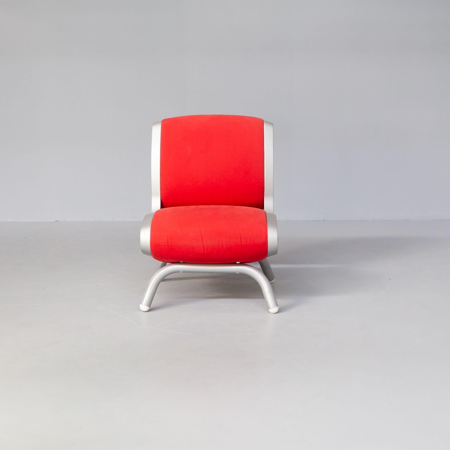 The impressive ‘Gluon’ chair has a lacquered steel and firm frame with rounded feet, ever more rare than the well known swivel based variant. The barrel supporting the seat rises from here and is made of silver tinted polyurethane with red fabric