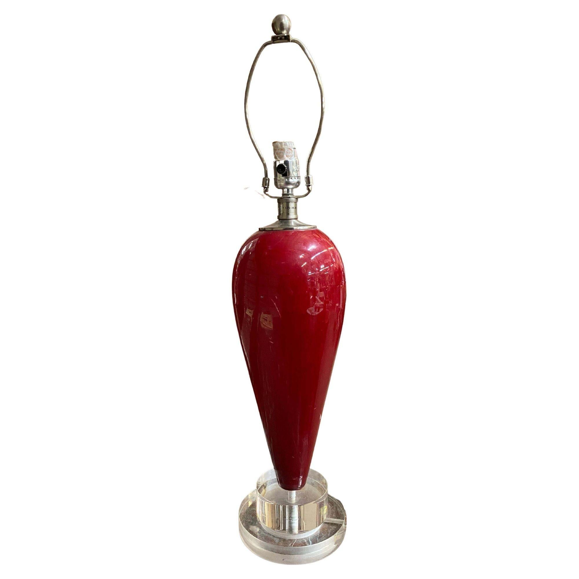 These 90s-style table lamps come in a bright red tear-drop shape made of ceramic. They sit on clear acrylic bases, giving them a modern look. These lamps add a pop of color and style to any room.