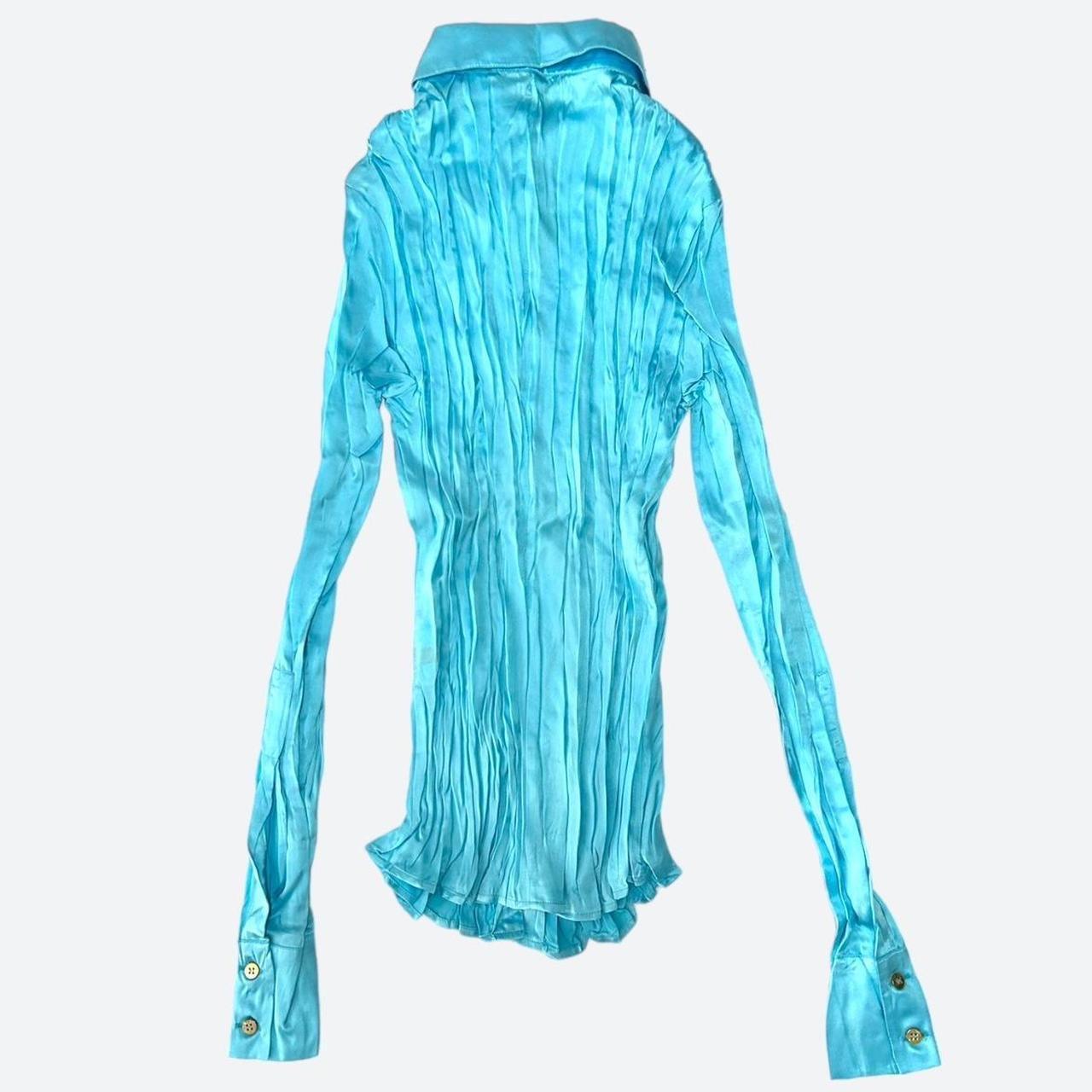 This 100% silk shirt in vibrant aqua blue has a unique pleated finish that adds texture to the rich glossy look of the silk, as well as some edge to the sophisticated style of this item.

The XS sized shirt is done up at the front in gold color