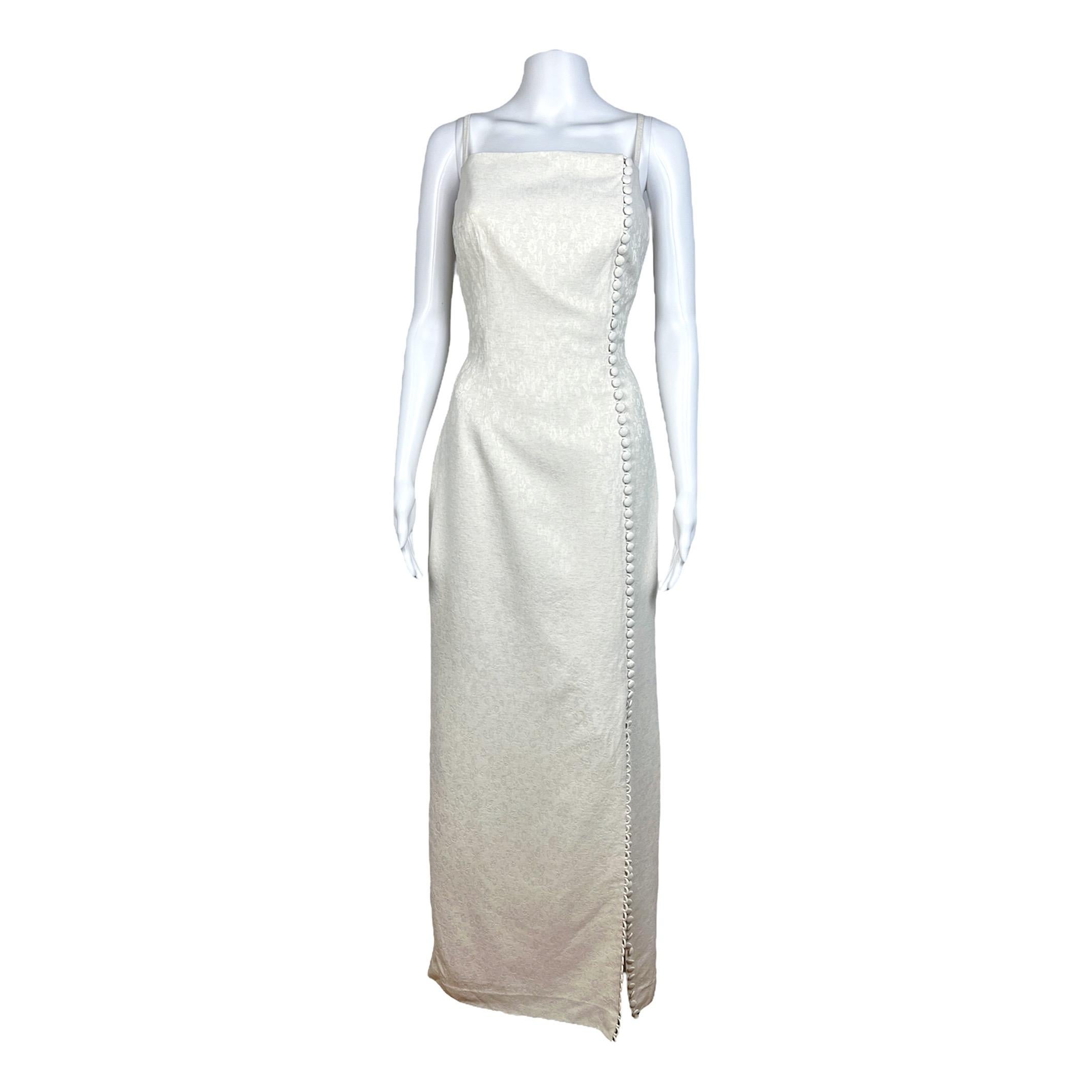 Exquisite and timeless, this stunning Valentino white gown from the early 90s features a delicate jacquard floral motif, complemented by covered buttons and a tasteful slit. Its elegance makes it the ideal choice for a rehearsal dinner. The buttons