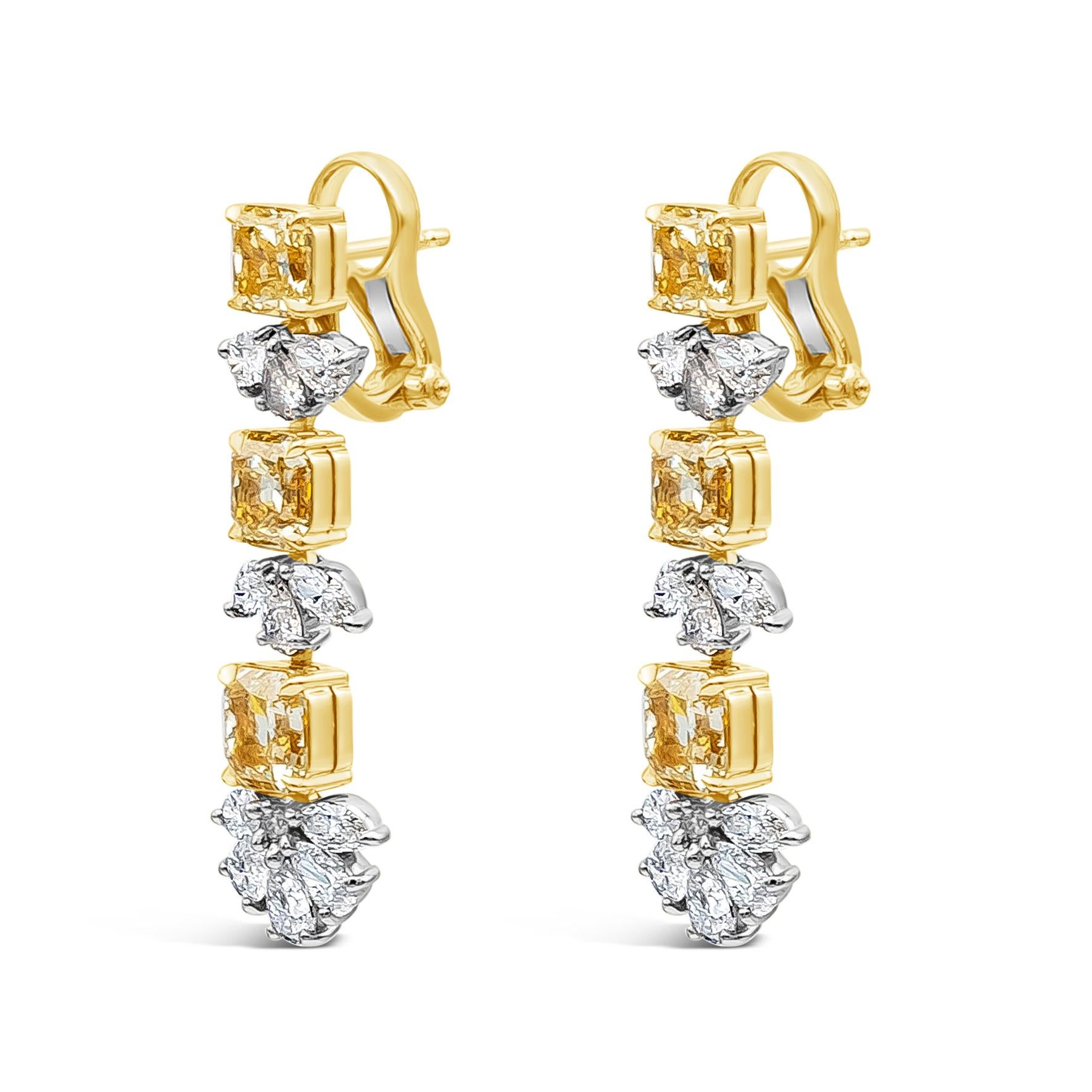 Elegantly crafted color rich high end drop earrings showcasing 6 vibrant radiant cut fancy yellow diamonds weighing 6.43 carats total, VS+ in clarity, set in a four prong 18k yellow gold basket. Intricately alternates with a cluster of mixed cut