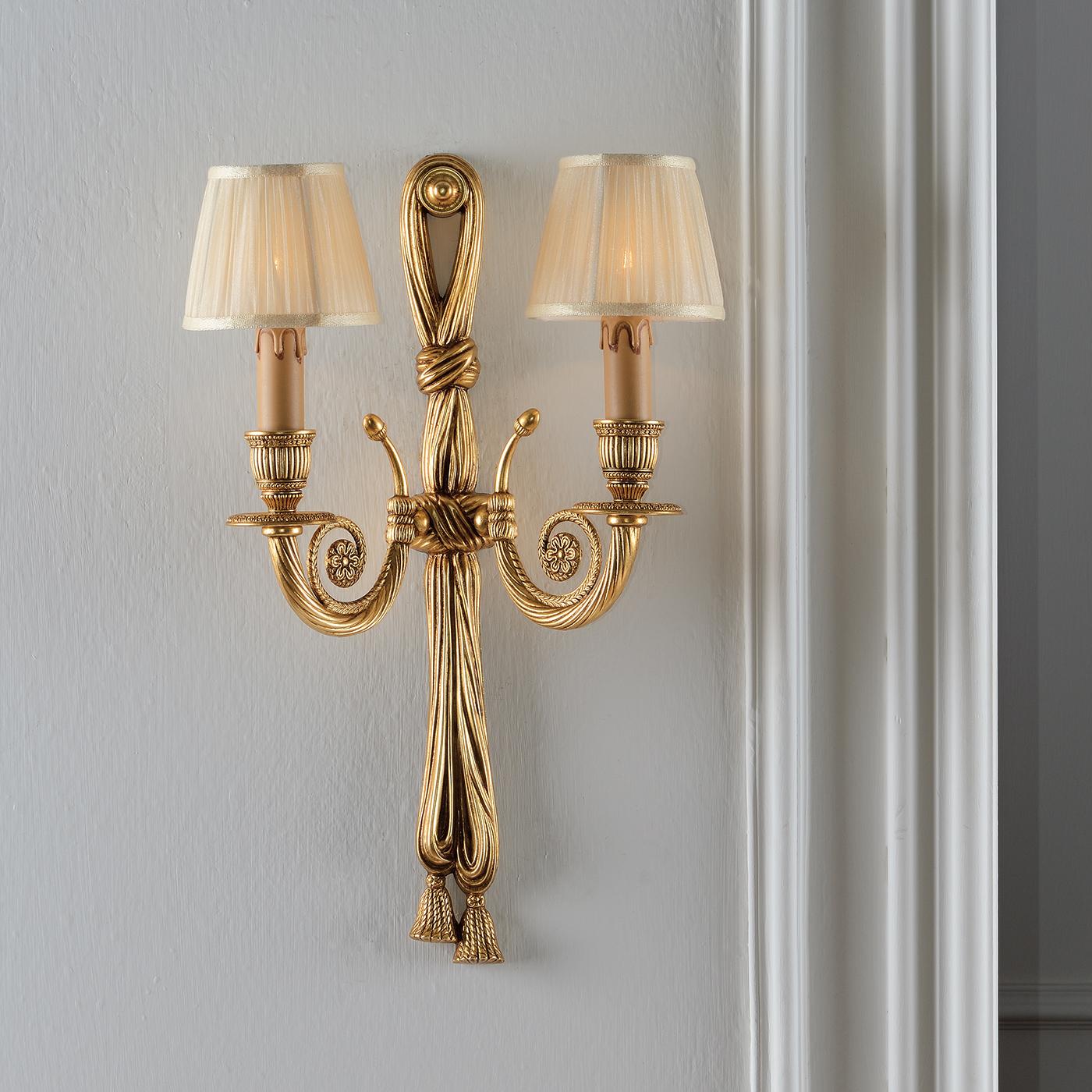 Featuring a brass structure decorated in a gold leaf patina, this stunning wall lamp with 2 lights, will add class and character to any room in a contemporary or classic style home. Complimenting the ornate brass work, are the ivory organza