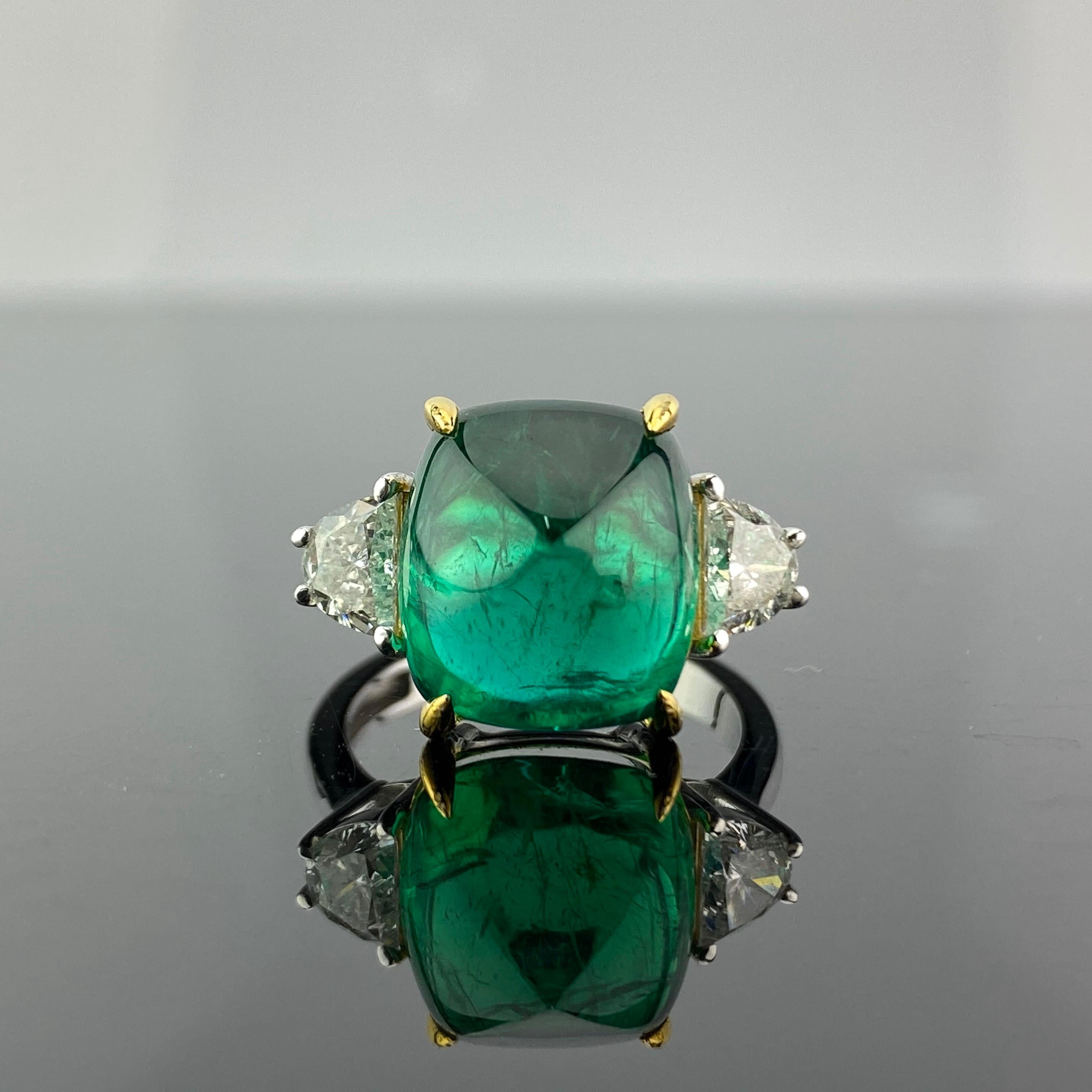 A one-of-a-kind three stone engagement ring, with a 9.15 carat transparent natural Zambian Emerald centre stone and 2 half-moon side stone diamonds. The emerald is of great lustre and has an ideal colour. All set in 18K white gold. Currently a ring