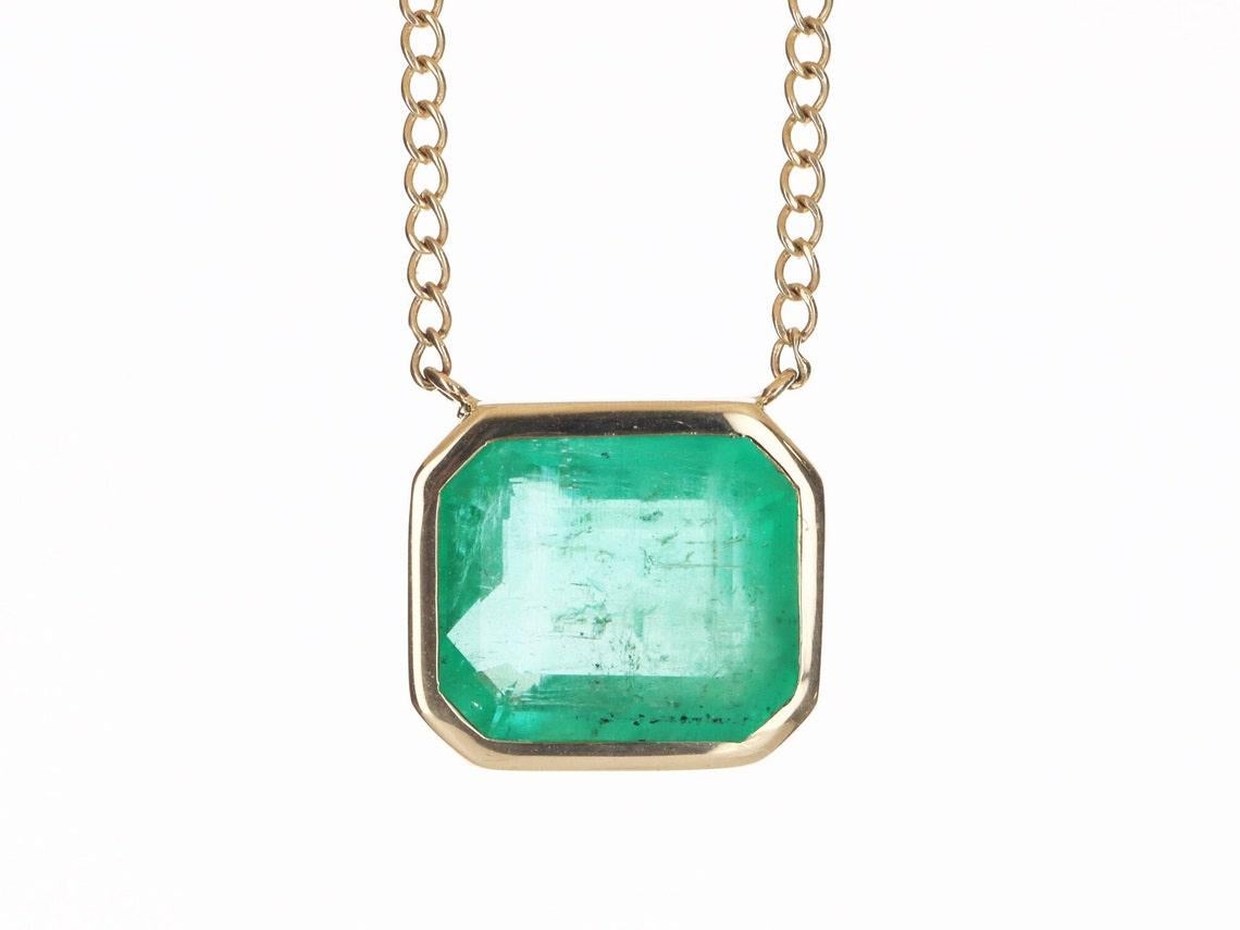 Take a glimpse of this one of a kind stunning, emerald and diamond statement necklace. The featured stone is a large, Colombian emerald-emerald cut with 8.80-carats of pure beauty! The stone displays an enchanting medium-green color, with a minimal