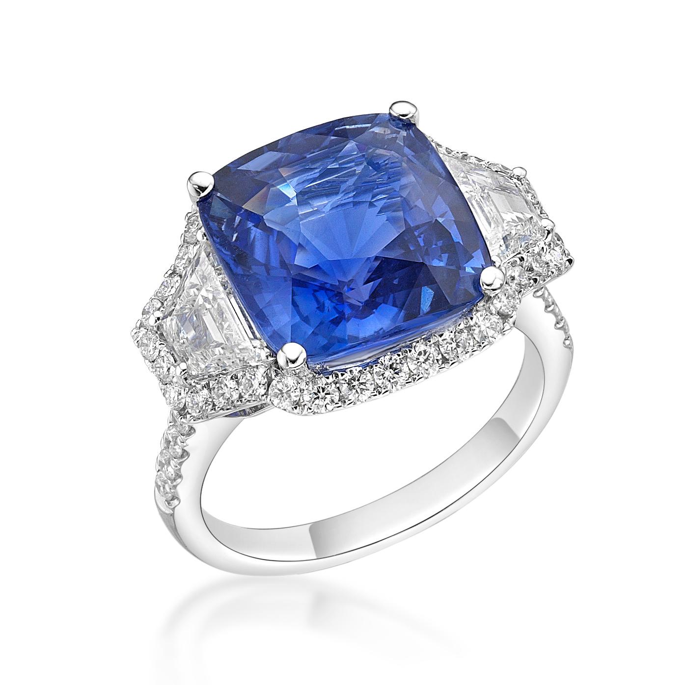 In the very center of this exquisite ring is a 9.16 ct unheated cushion blue sapphire originated from Sri Lanka. Flanking the gemstone are two trapeze diamonds surrounded by a halo of sparkling diamonds. This ring can be resized upon request.