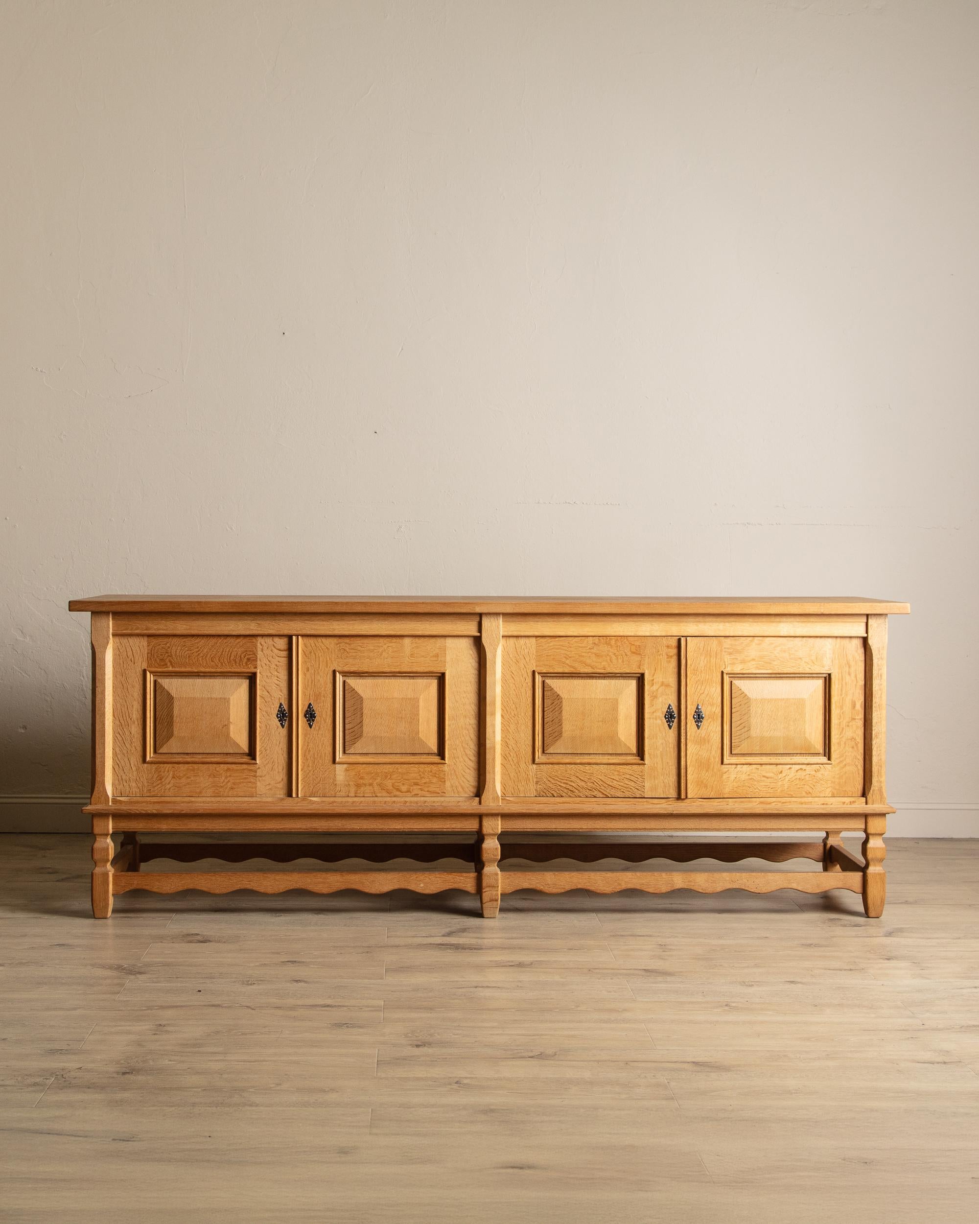 Este gran aparador vintage presenta un rico acabado en roble y puertas finamente paneladas, combinando el diseño clásico con la funcionalidad práctica. Su elegante base festoneada y sus patas torneadas añaden un toque tradicional, mientras que los