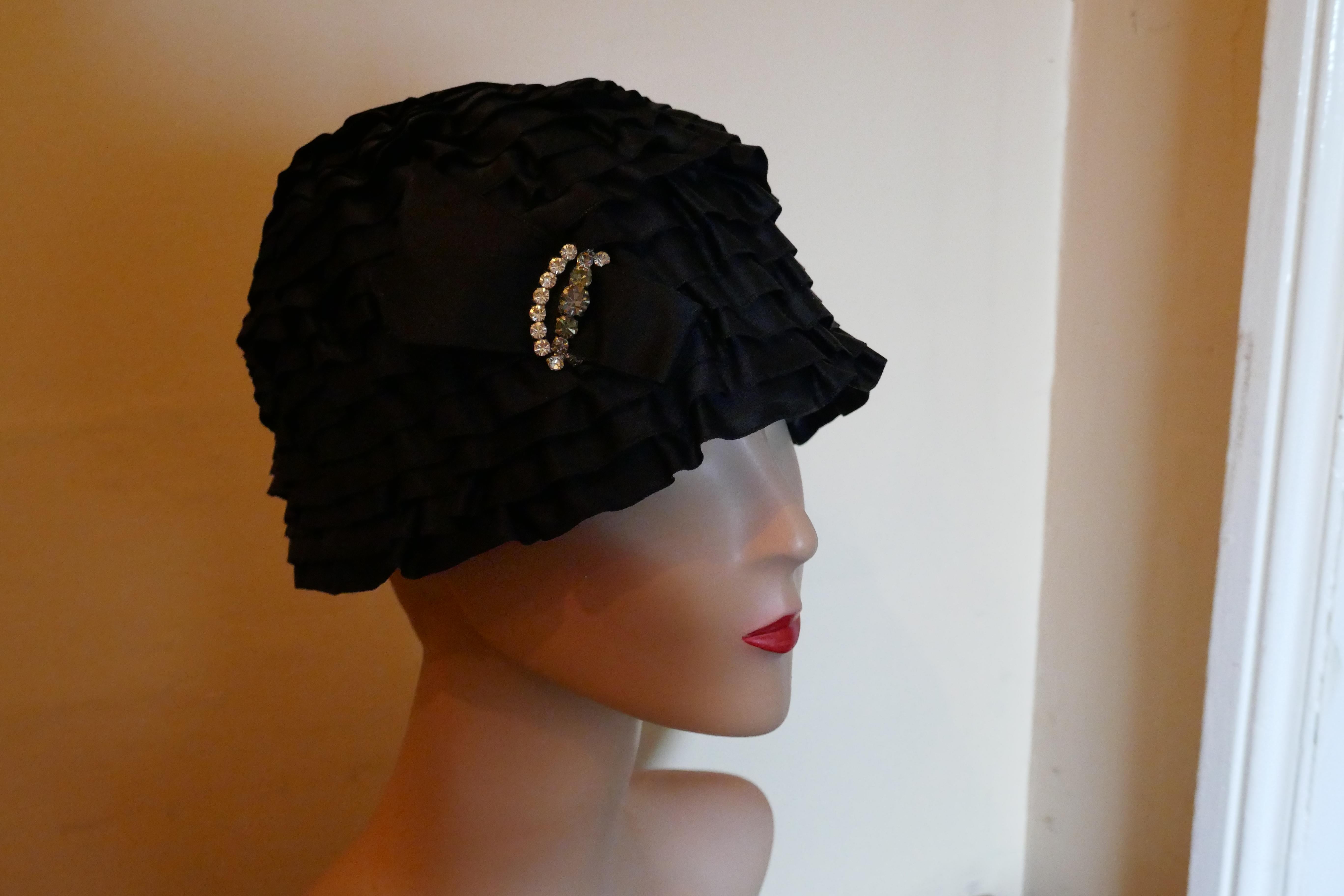 920’s Tight Fitting Black Satin Evening Hat By Dolores of London and Paris 

Roaring ‘20s Flapper Close Fitting Satin Ribbon Evening Cloche Hat, by Delores London and Paris  

Absolute fun, this is a close fitting hat made on net with rows of