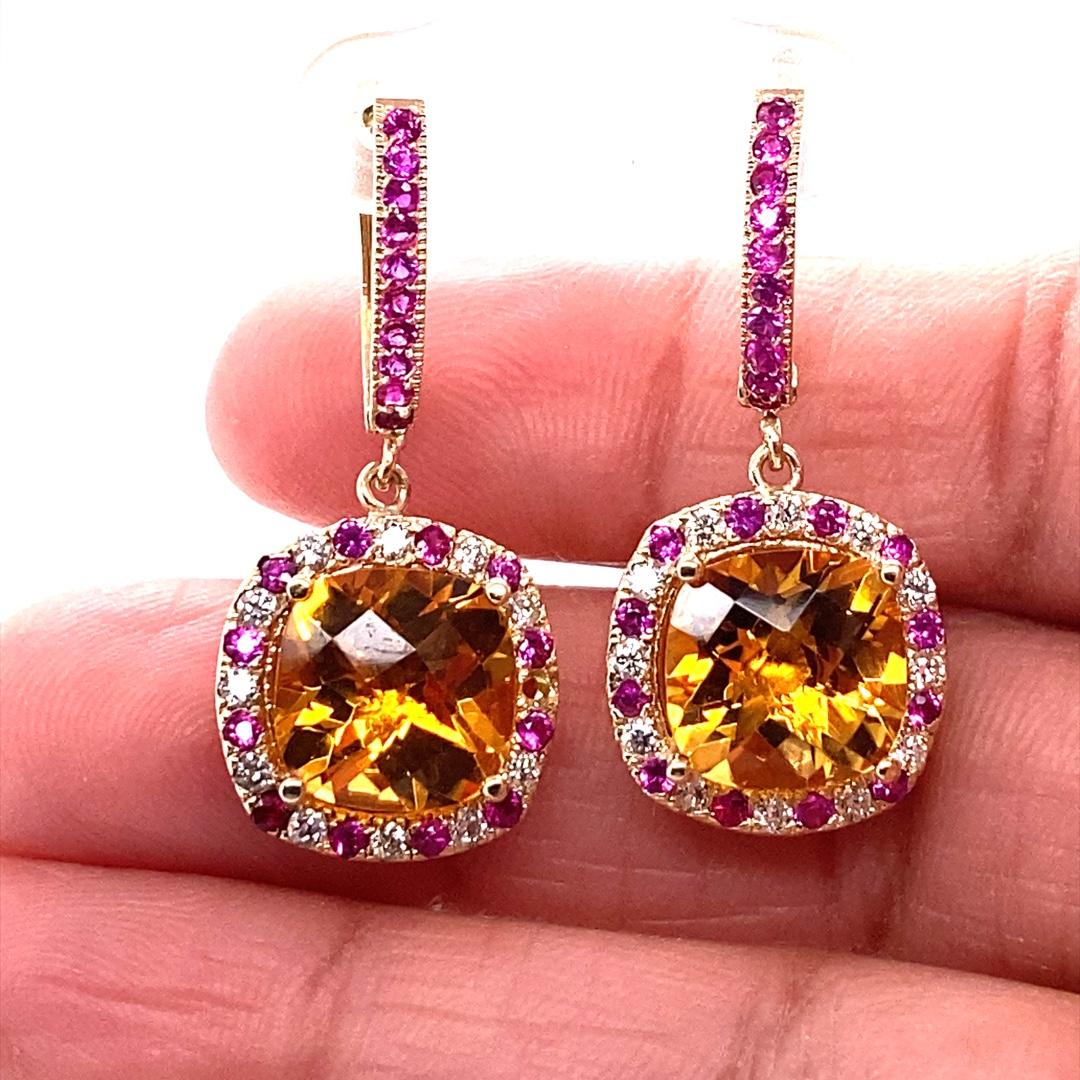 These lovely earrings have 2 vibrant Cushion Cut Citrine Quartz that weigh 7.85 carats.  The centers are surrounded by alternating Pink Sapphires that weigh 0.91 carats and 24 Round Cut Diamonds that weigh 0.46 carats (Clarity: SI2, Color: F). The