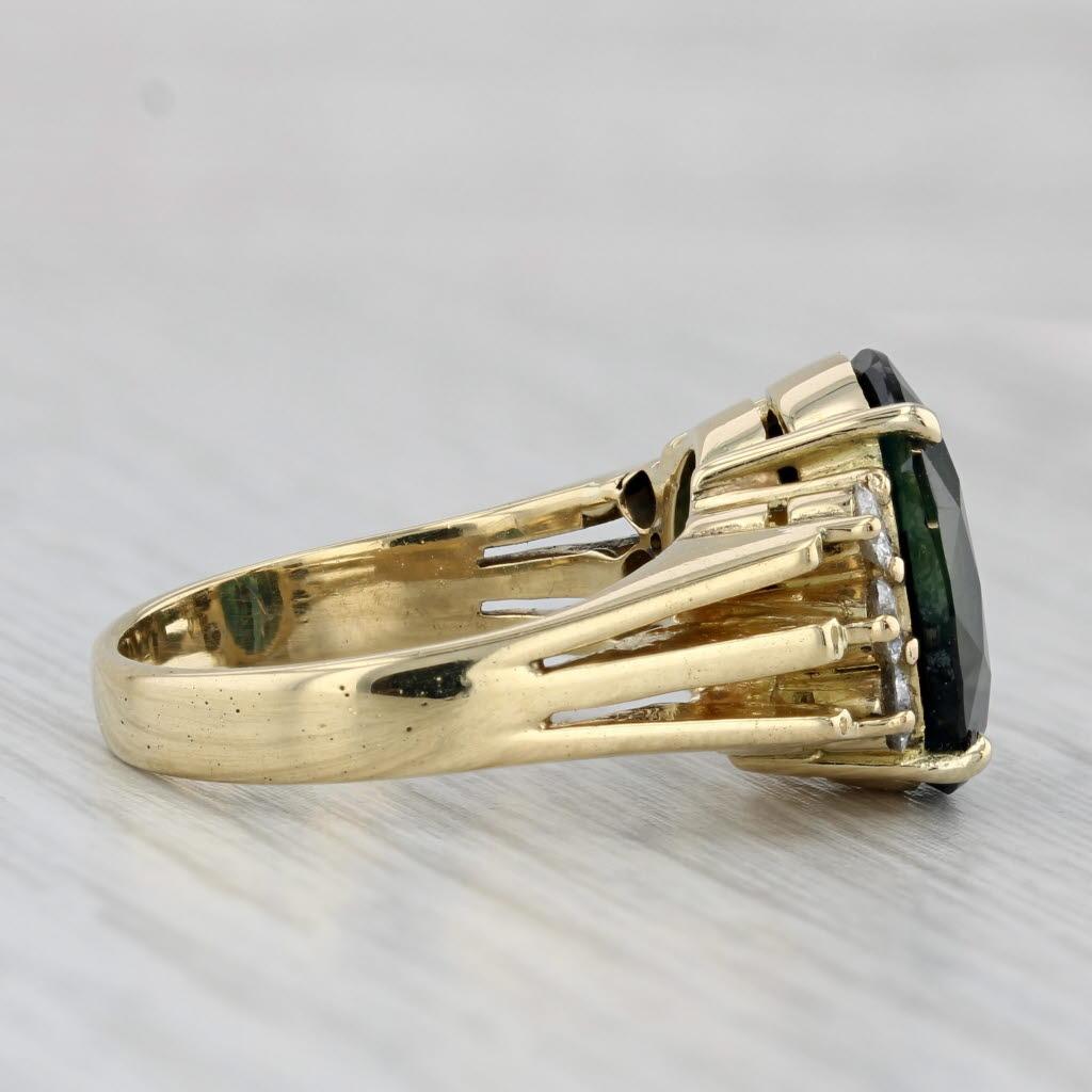 This stunning ring features a natural, untreated, dark teal sapphire framed by natural diamonds, atop a polished yellow gold band. GIA paperwork on the sapphire is included with the purchase of the ring. 

Gemstone Information:
- Natural Sapphire