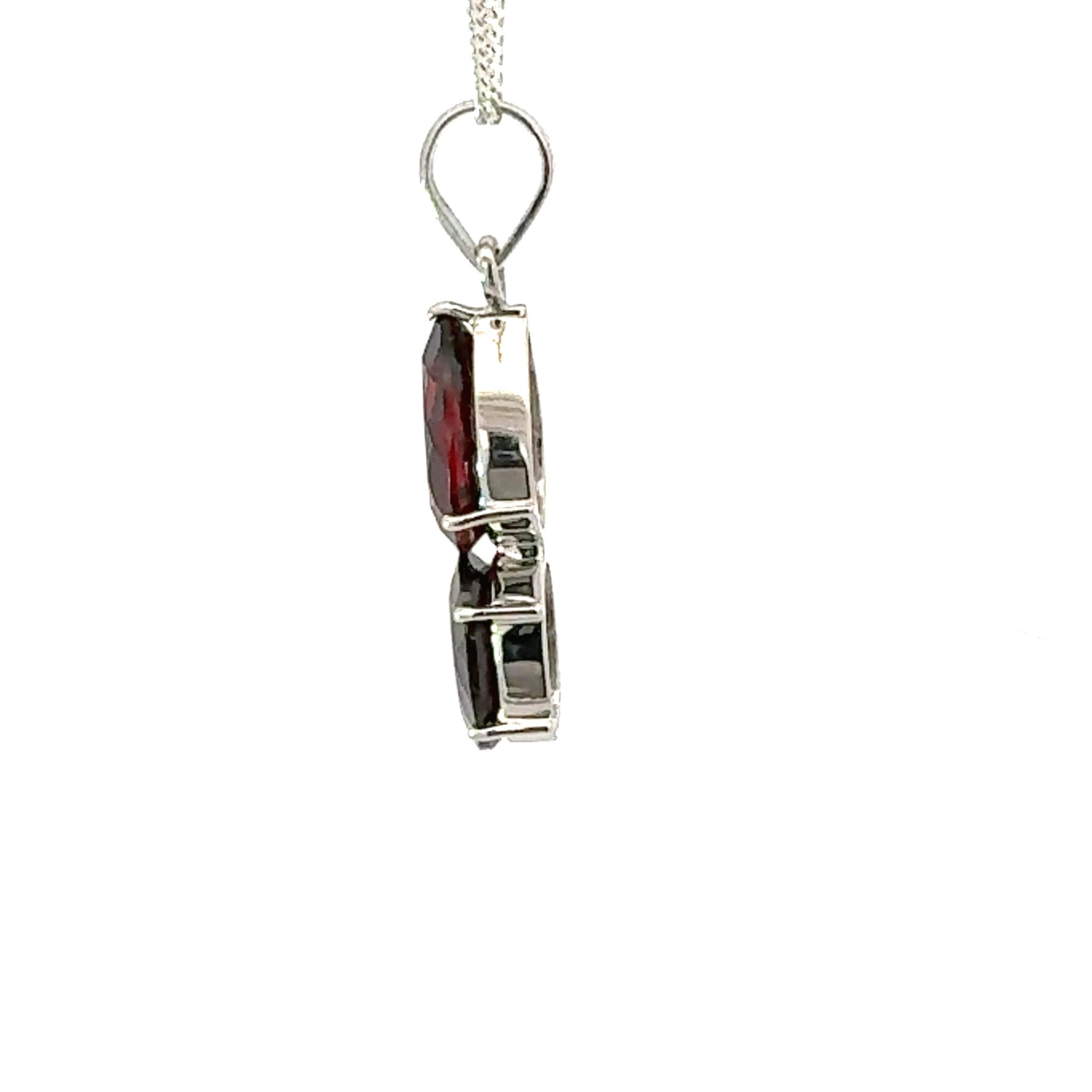 Questo ciondolo a goccia di granato rosso intenso con gemma a taglio pera e ovale è realizzato a mano e presenta due gemme di granato rosso intenso, una a taglio pera e una a taglio ovale, graziosamente impilate in un design verticale. Incastonate