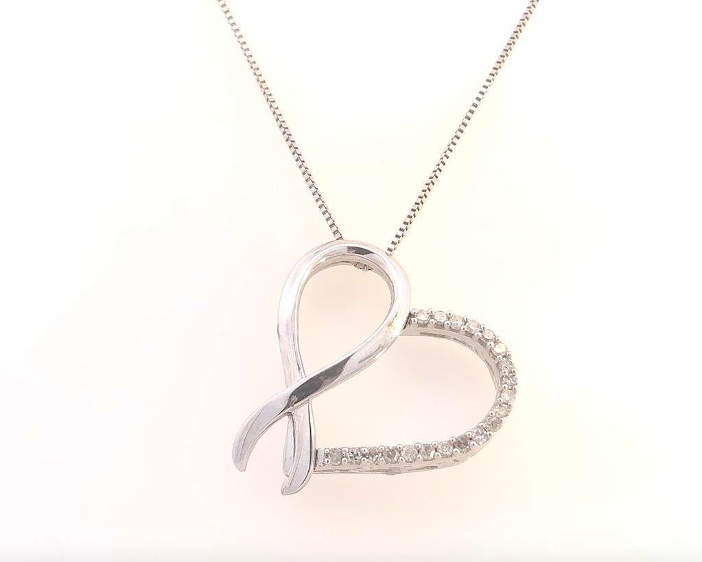 Striking the perfect balance of delicate and dramatic appeal, this ribbon and heart accent pendant is composed of sterling silver. The one side of the heart features a beautiful embellishment of prong set round cut diamonds, which makes it eye