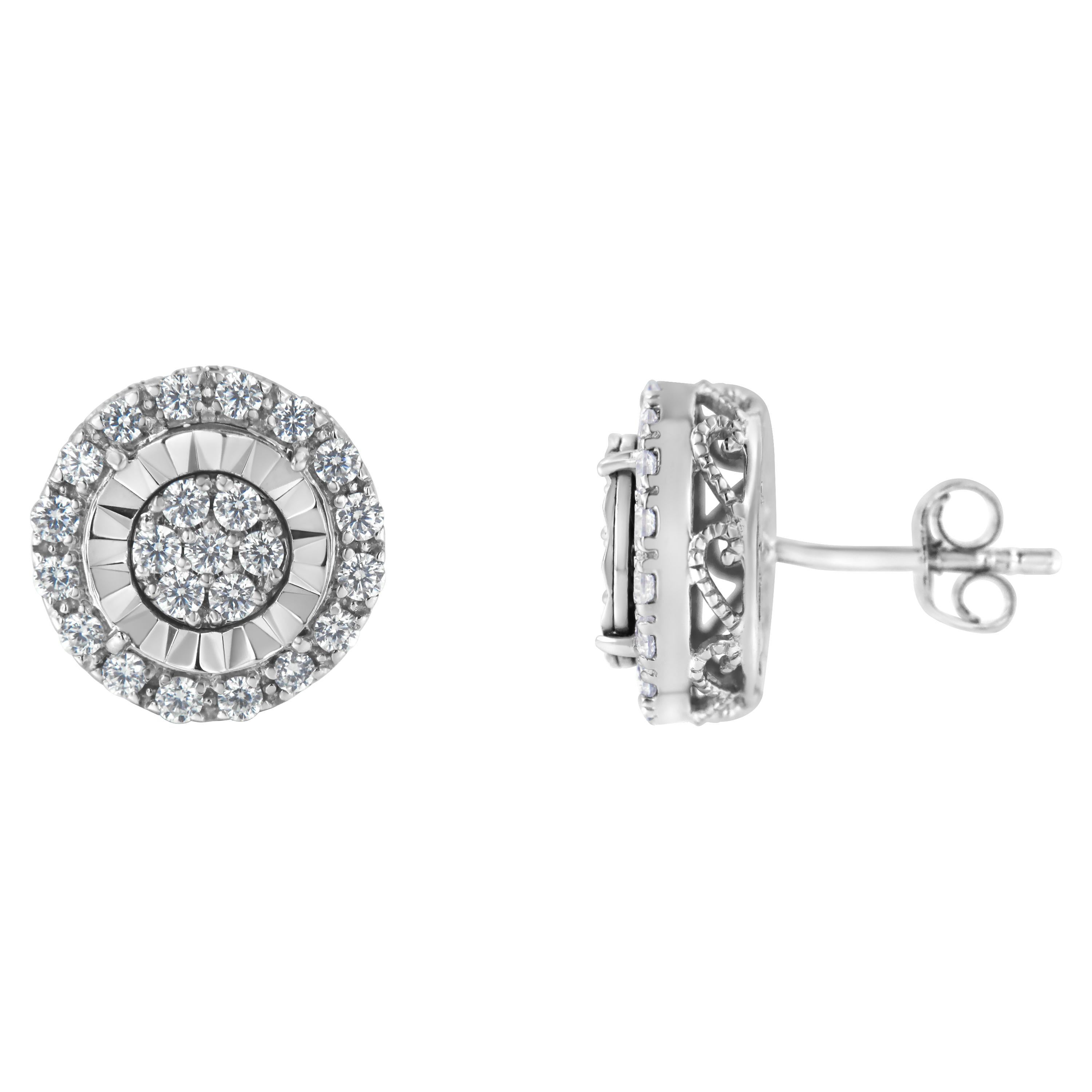 Beautiful and delicate, these sterling silver 1ct diamond cluster stud earrings feature 7 round cut diamonds encircled by a halo of an additional 16 diamonds. All prong set diamonds are mounted on top of a filigree decorated box. With a push back